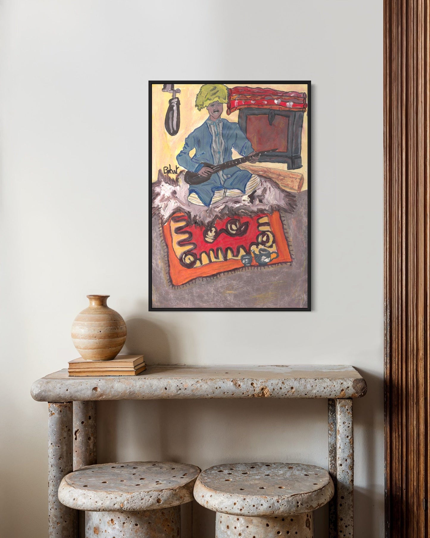 Framed artwork on a wall above a rustic table with decorative items.