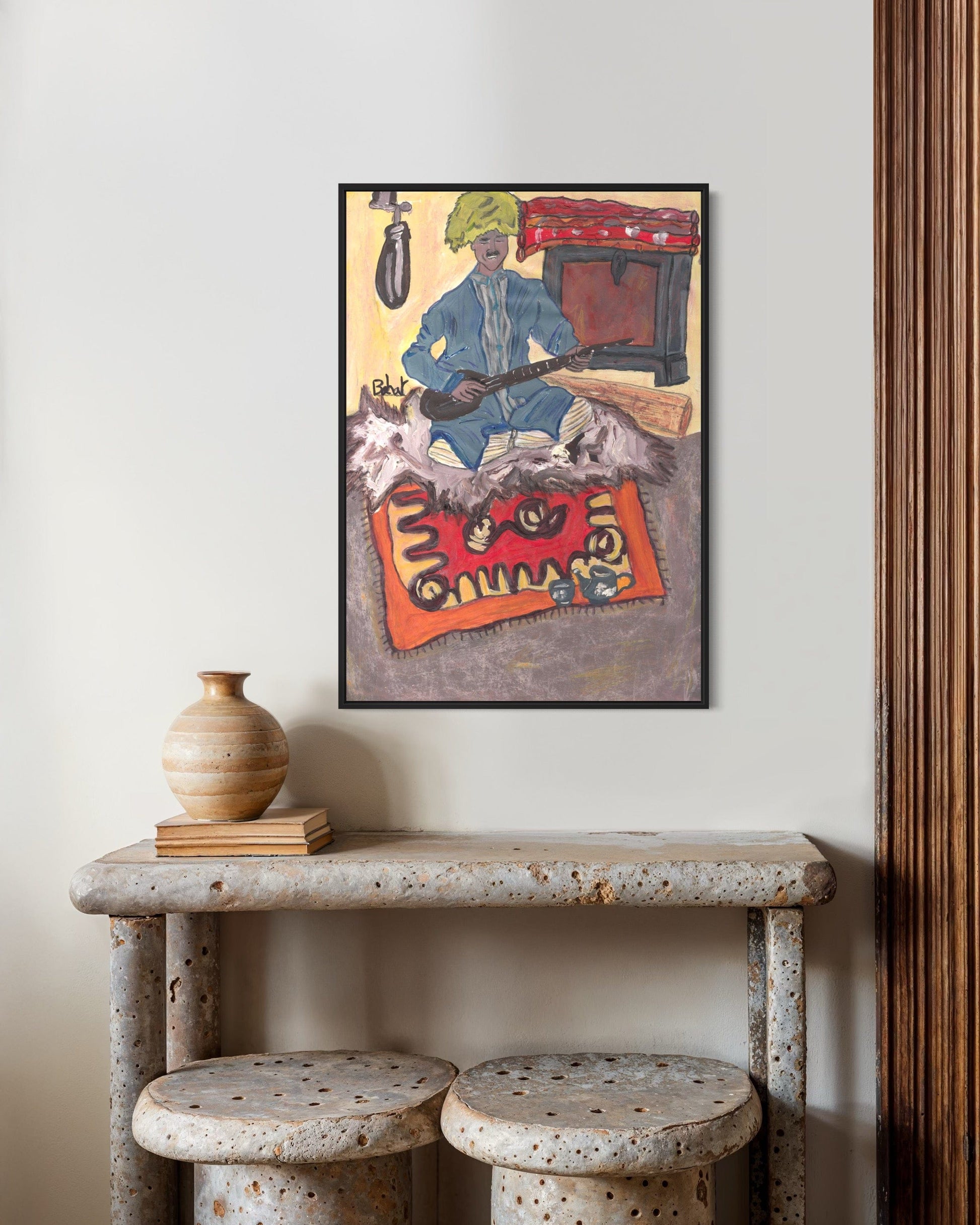Framed artwork on a wall above a rustic table with decorative items.