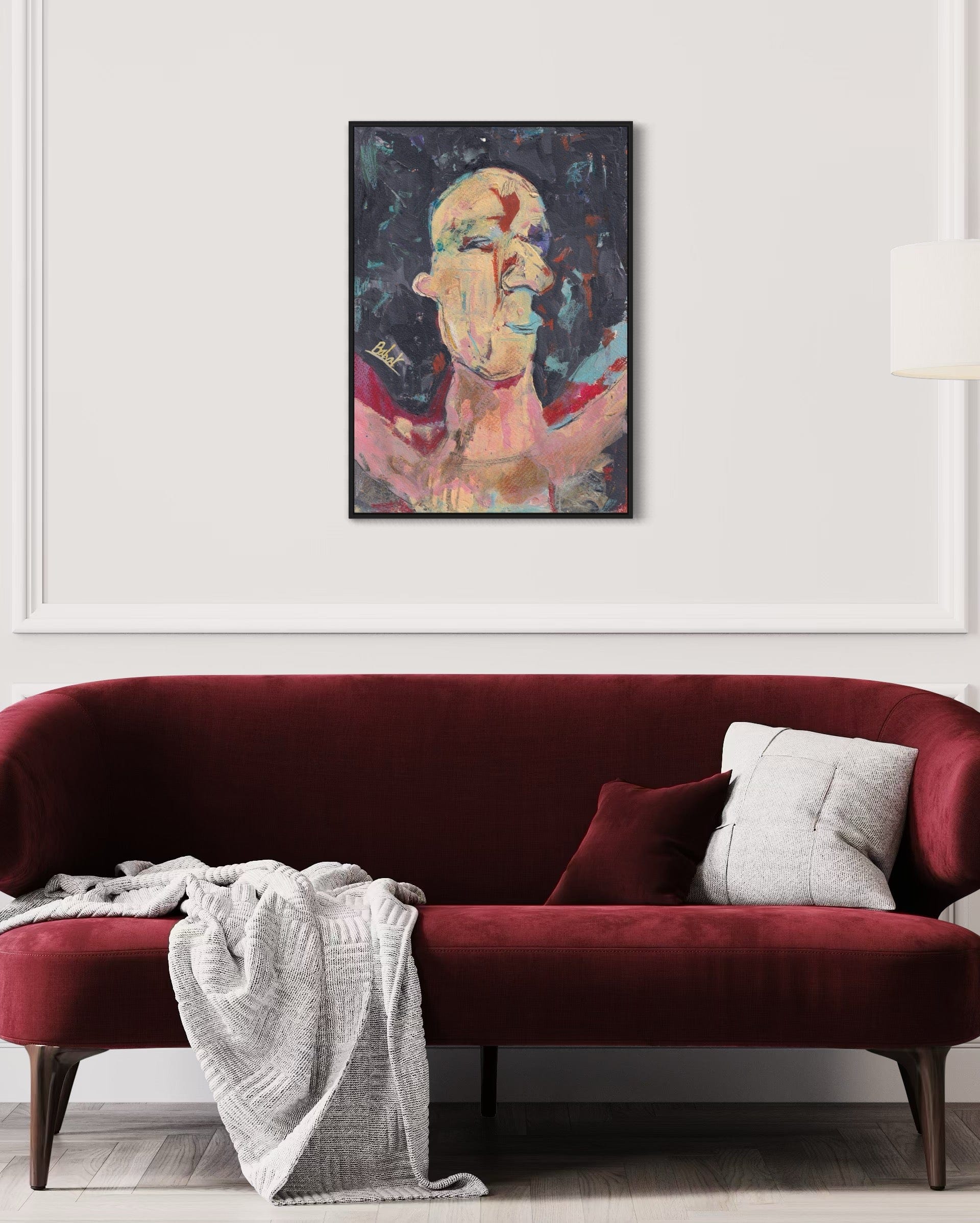 Red sofa with a white blanket and gray pillow, framed artwork above on a white wall.