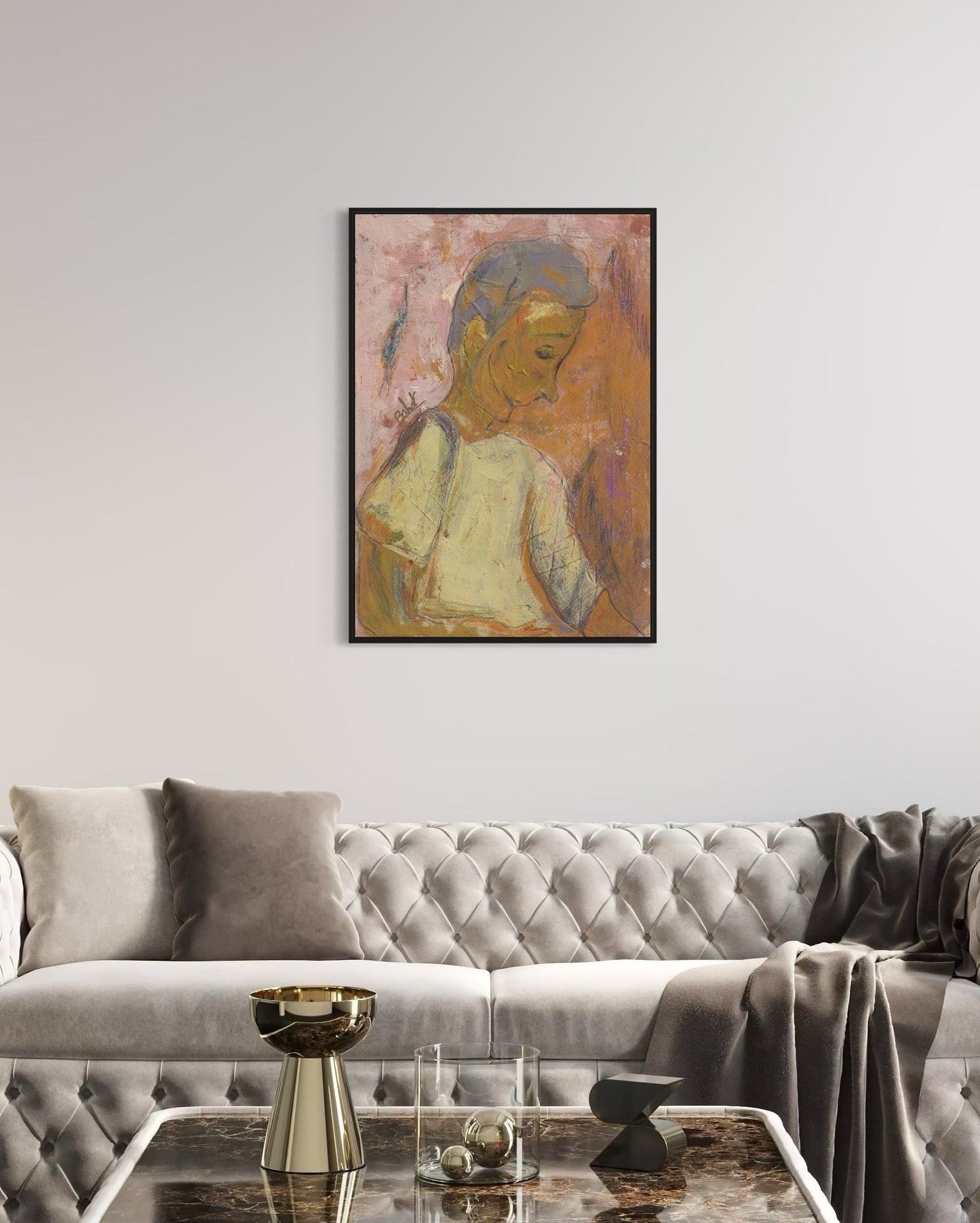 Living room with a gray tufted sofa, gold side table, and framed artwork on the wall.