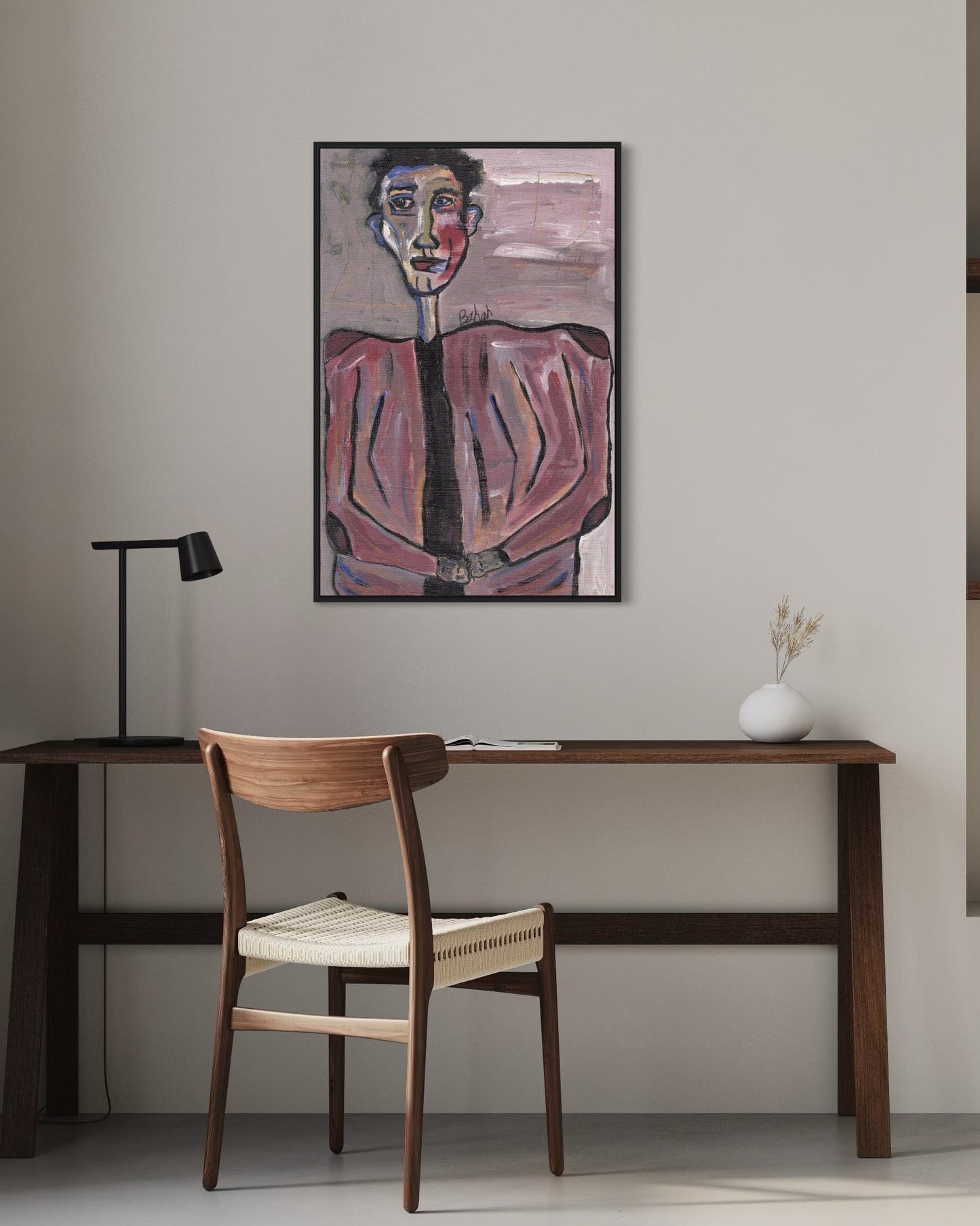 Artistic portrait on a wall above a wooden desk with a chair.