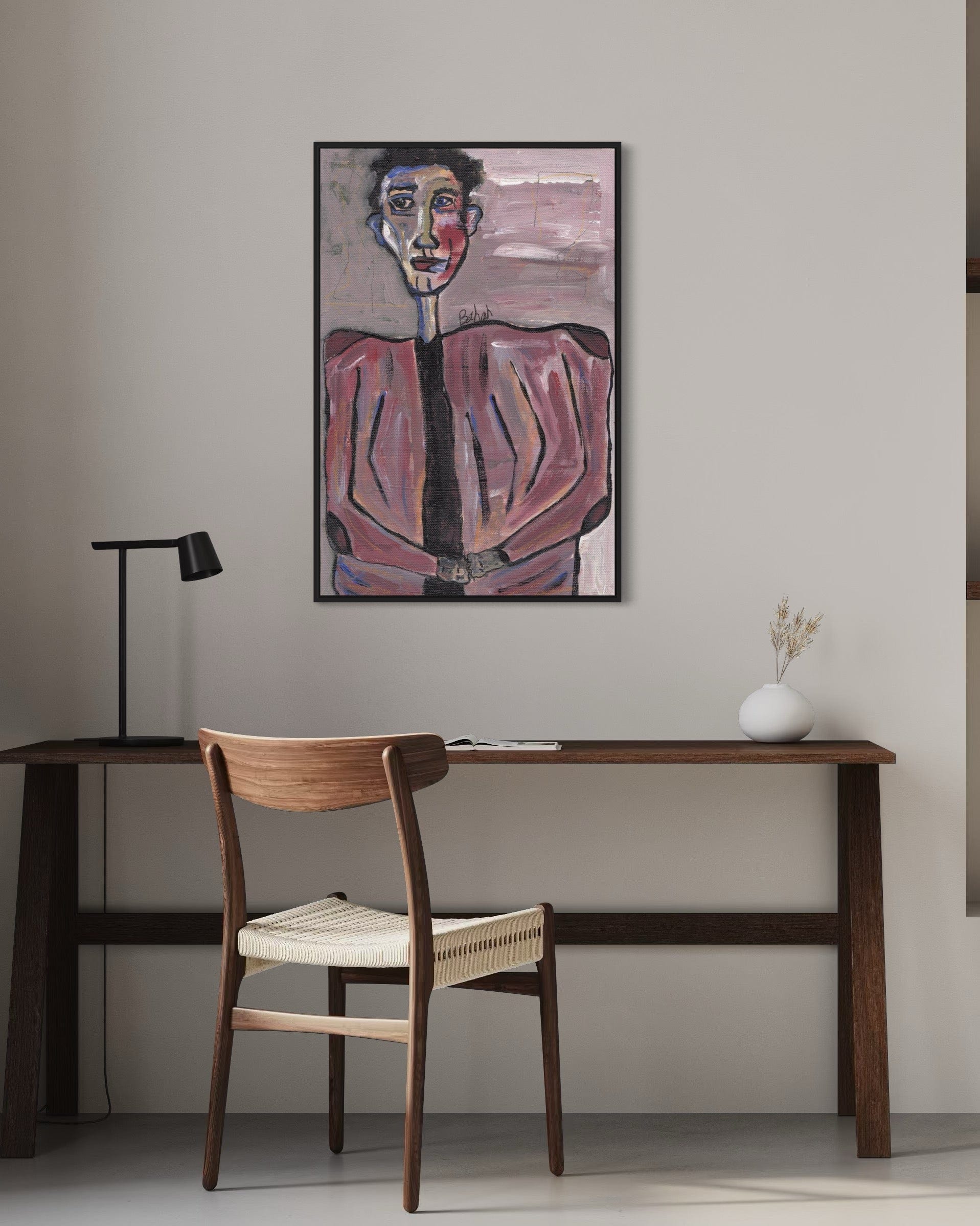 Artistic portrait on a wall above a wooden desk with a chair.