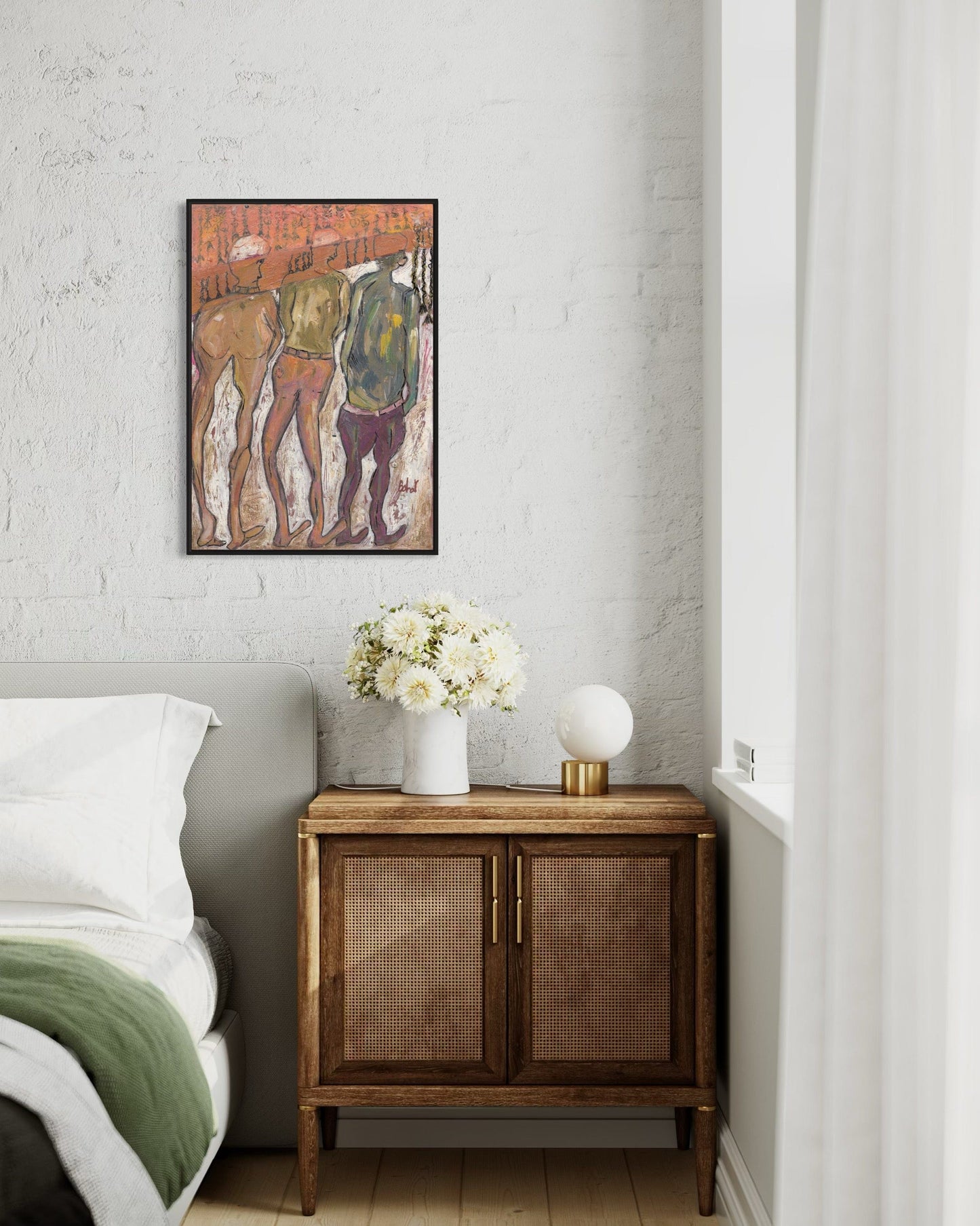 Wooden side table with a vase of flowers next to a bed, with a framed artwork on the wall.