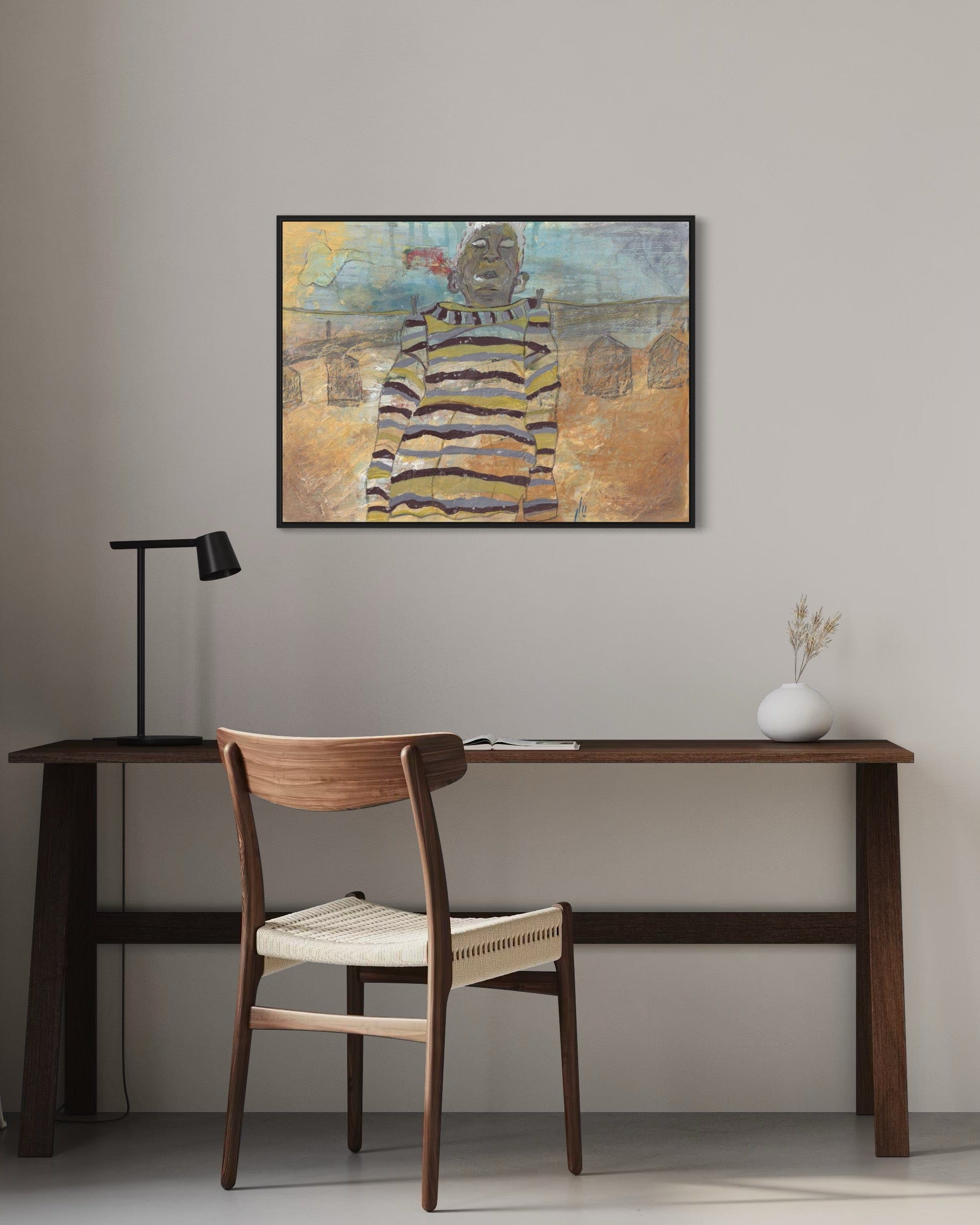 Home office with wooden desk, chair, and framed artwork on the wall.
