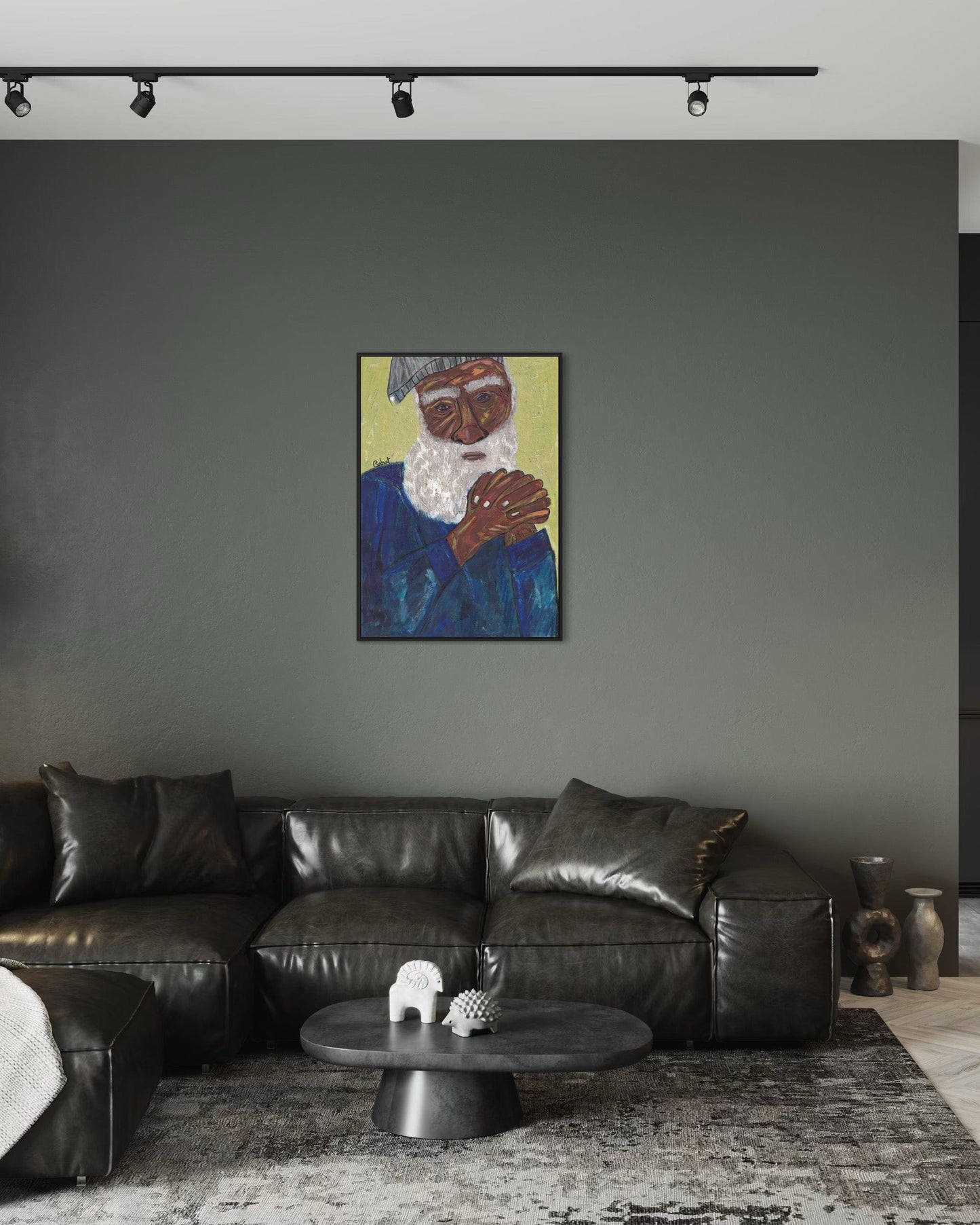 Living room with a black leather sofa, round coffee table, and a painting of an elderly man on the wall.