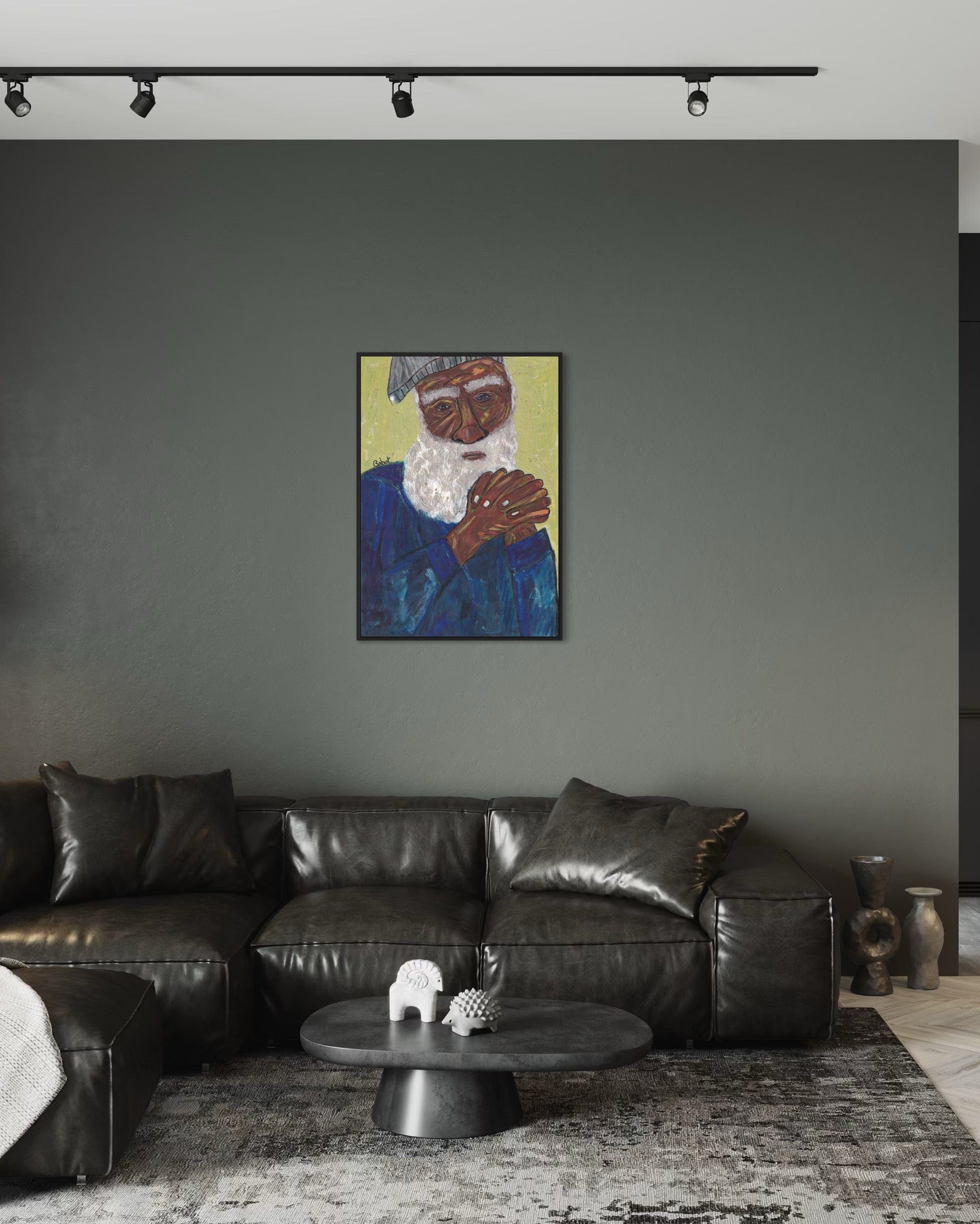 Living room with a black leather sofa, round coffee table, and a painting of an elderly man on the wall.