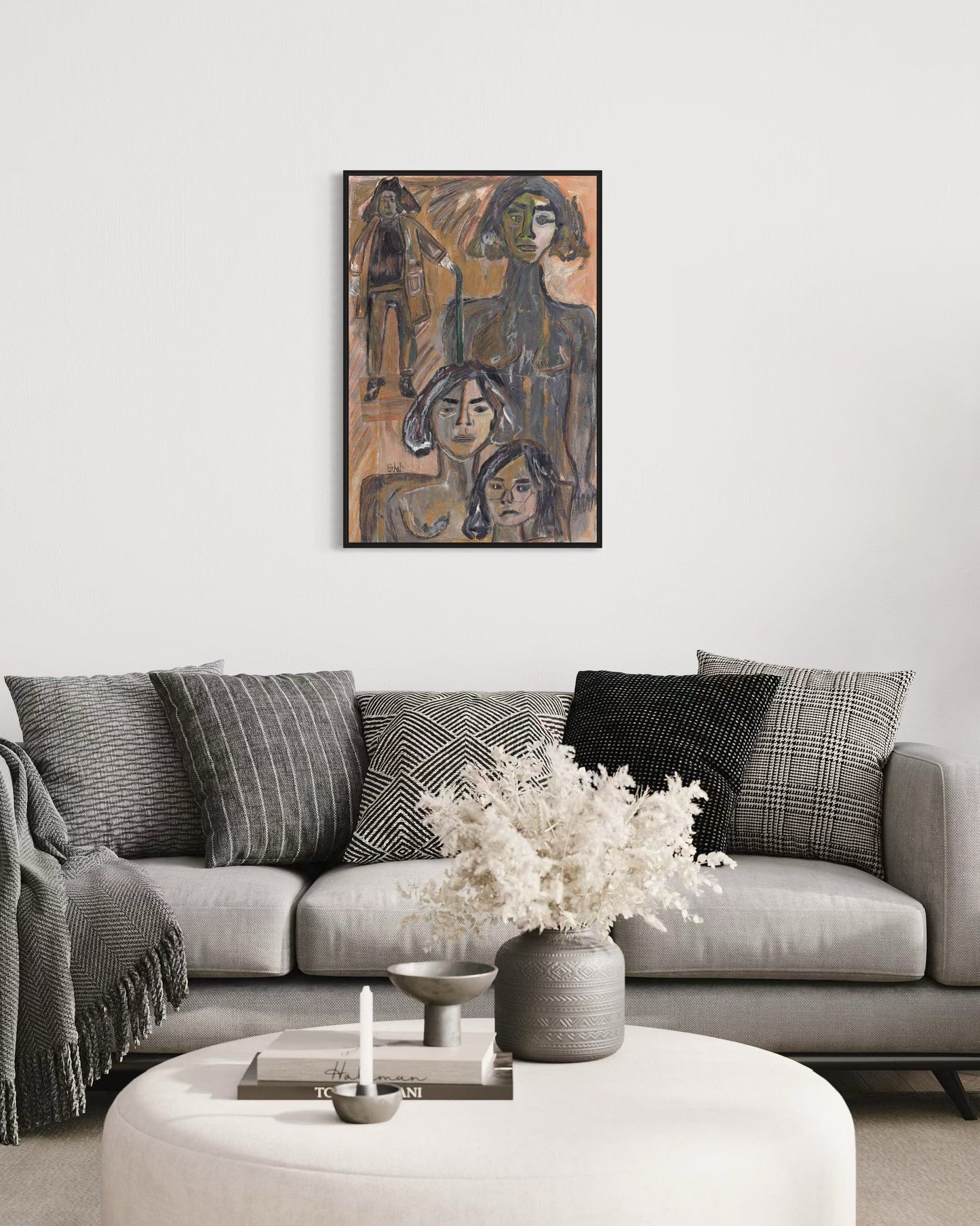 Living room with a gray sofa, decorative pillows, a vase with flowers, and a framed artwork on the wall.