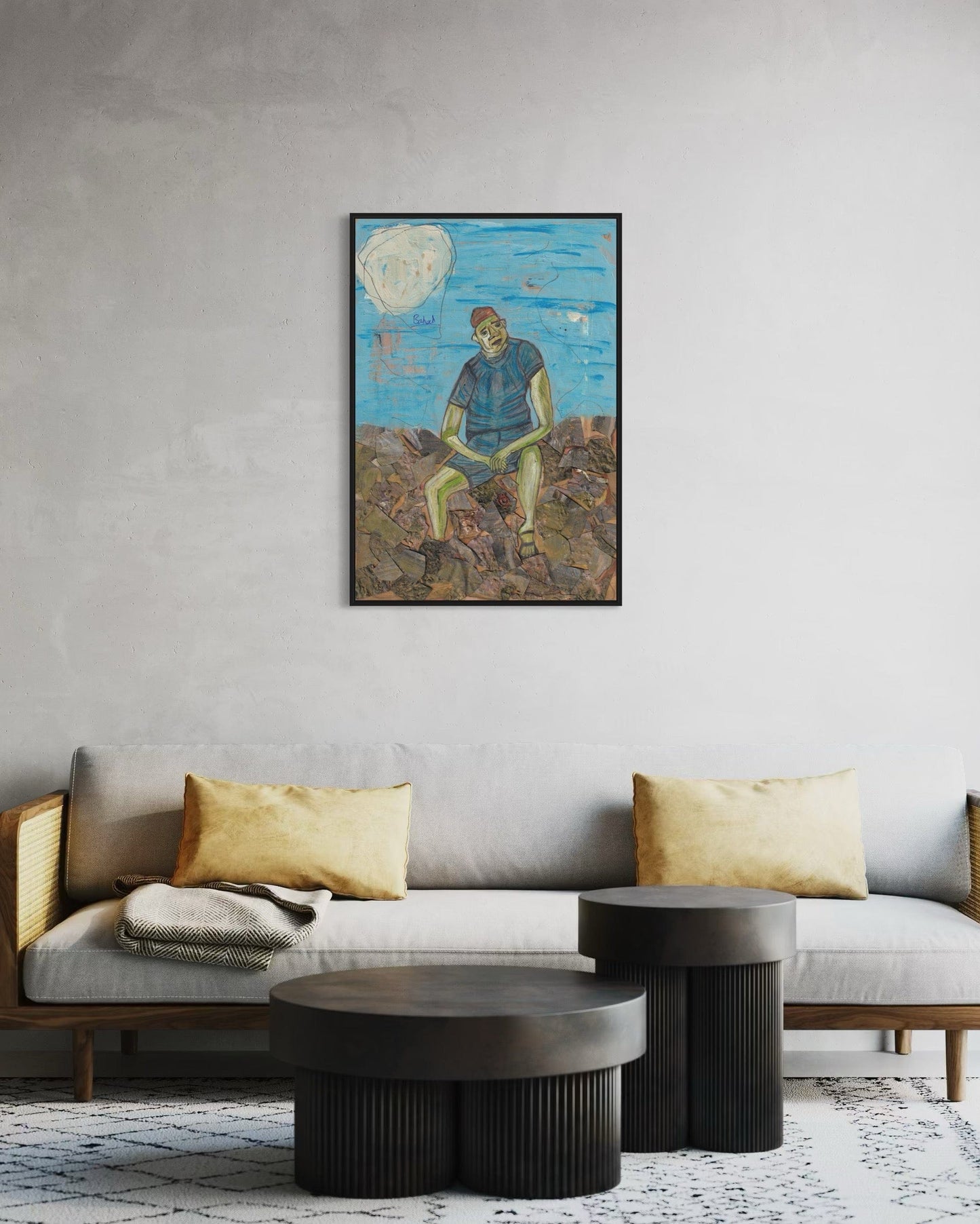 Living room with a gray sofa, round coffee table, and wall art of a person sitting on rocks.
