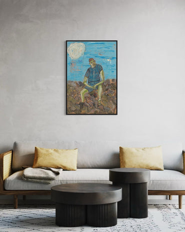 Living room with a gray sofa, round coffee table, and wall art of a person sitting on rocks.