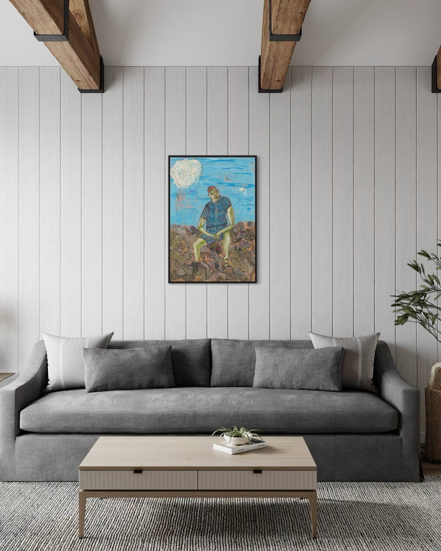 Gray sofa in a living room with a painting on the wall and a coffee table.