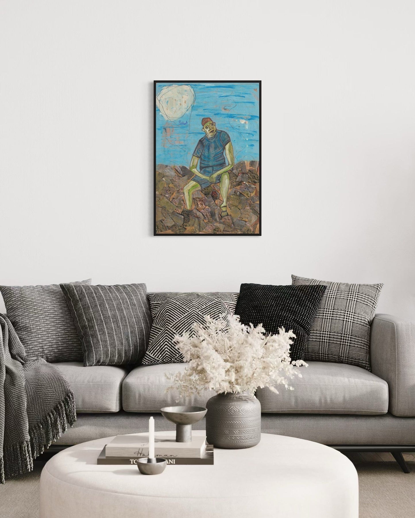 Living room with a gray sofa, decorative pillows, a vase with flowers, and a framed artwork on the wall.