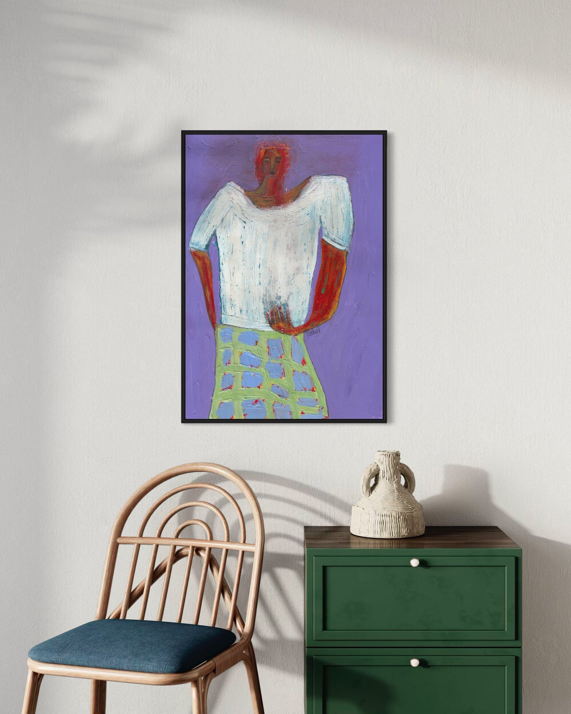Framed abstract art on a wall with a chair and green cabinet below.