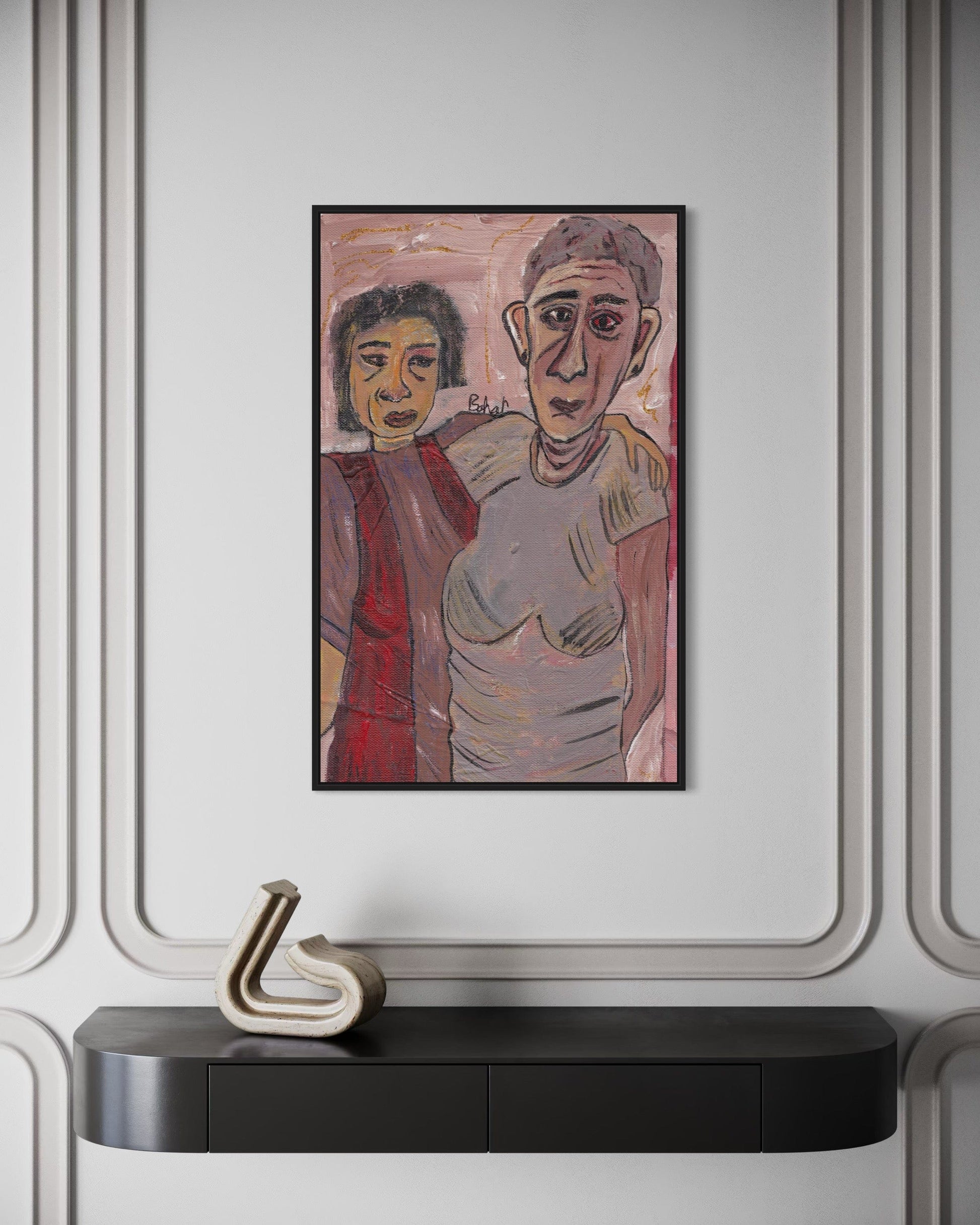 Framed artwork of two people on a wall above a black console table with a decorative object.