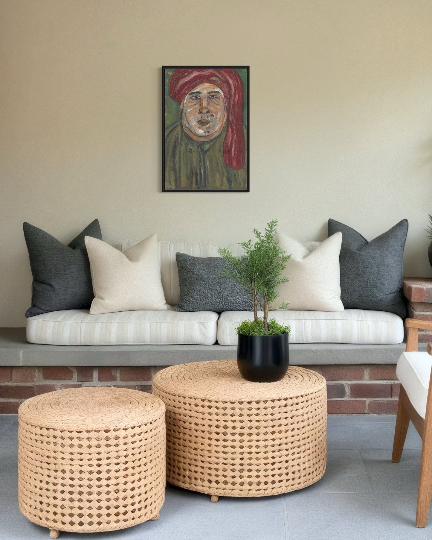 Living room with a sofa, ottomans, and a plant, featuring a painting on the wall.
