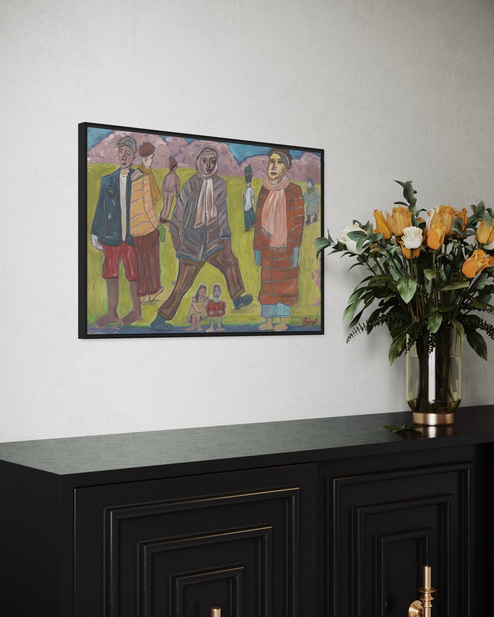 Framed artwork on a wall above a black cabinet with a vase of flowers.
