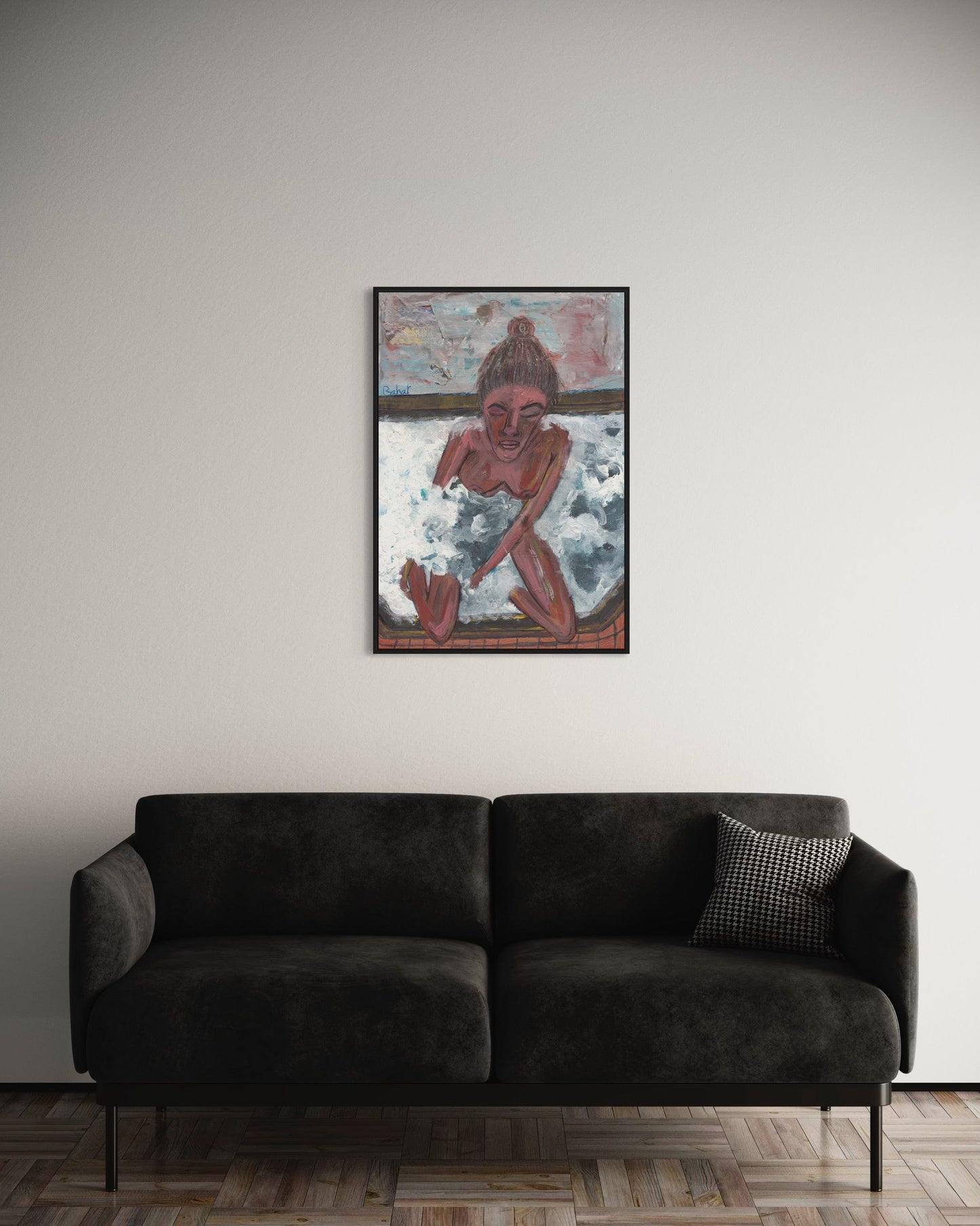 Framed artwork above a dark gray sofa in a room with a neutral color scheme.