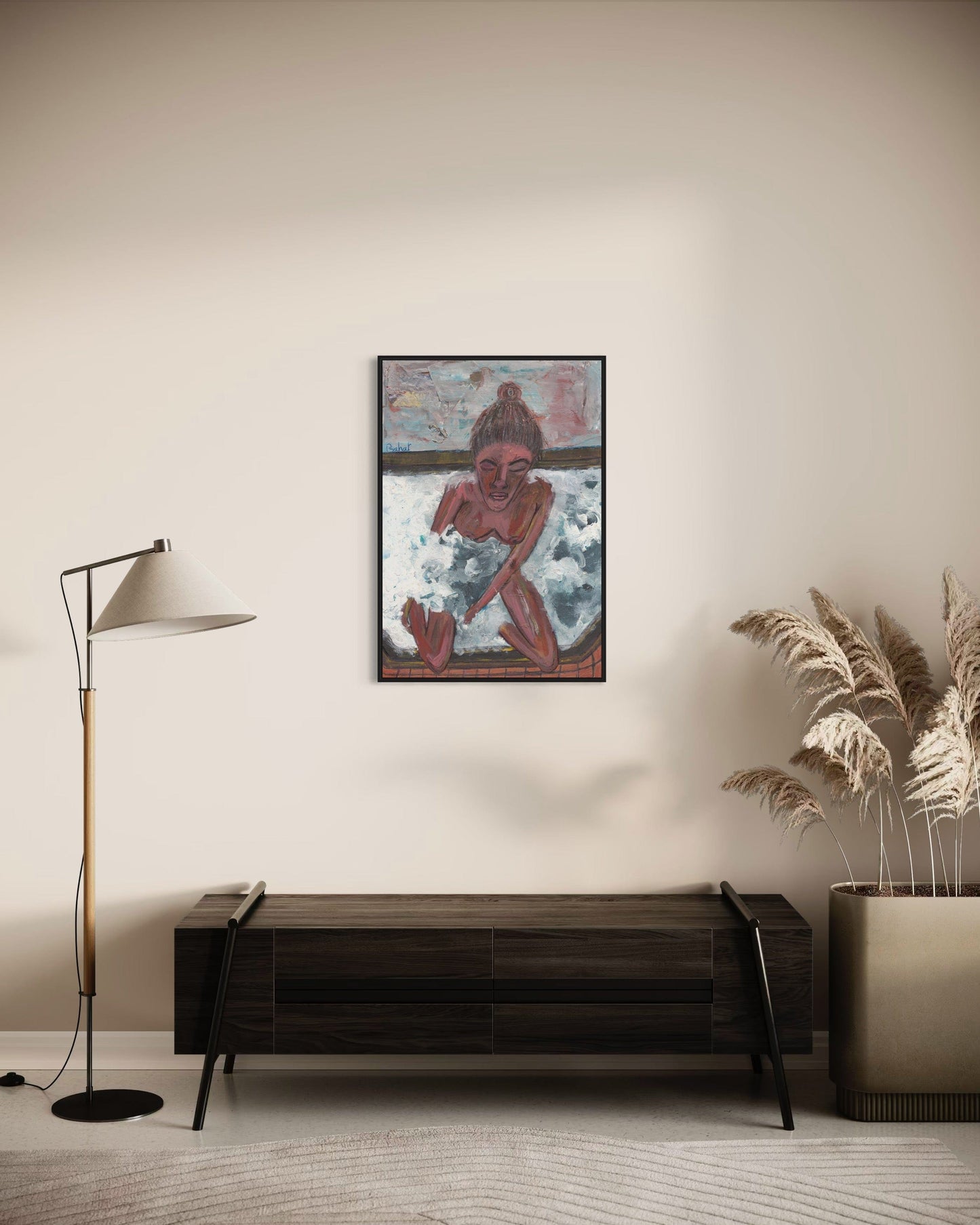 Framed artwork on a wall above a wooden console table in a room with a lamp and plant.