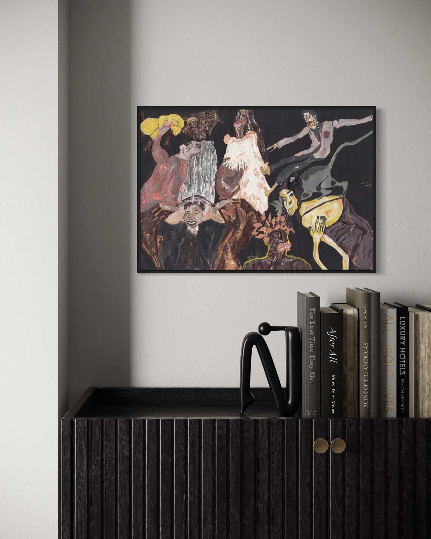 Framed abstract artwork on a wall above a shelf with books