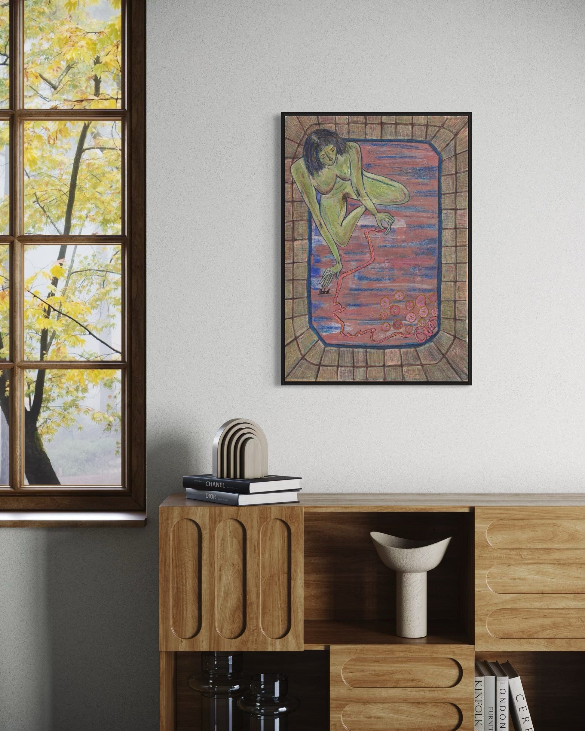 Framed artwork on a wall above a wooden cabinet with decor items.