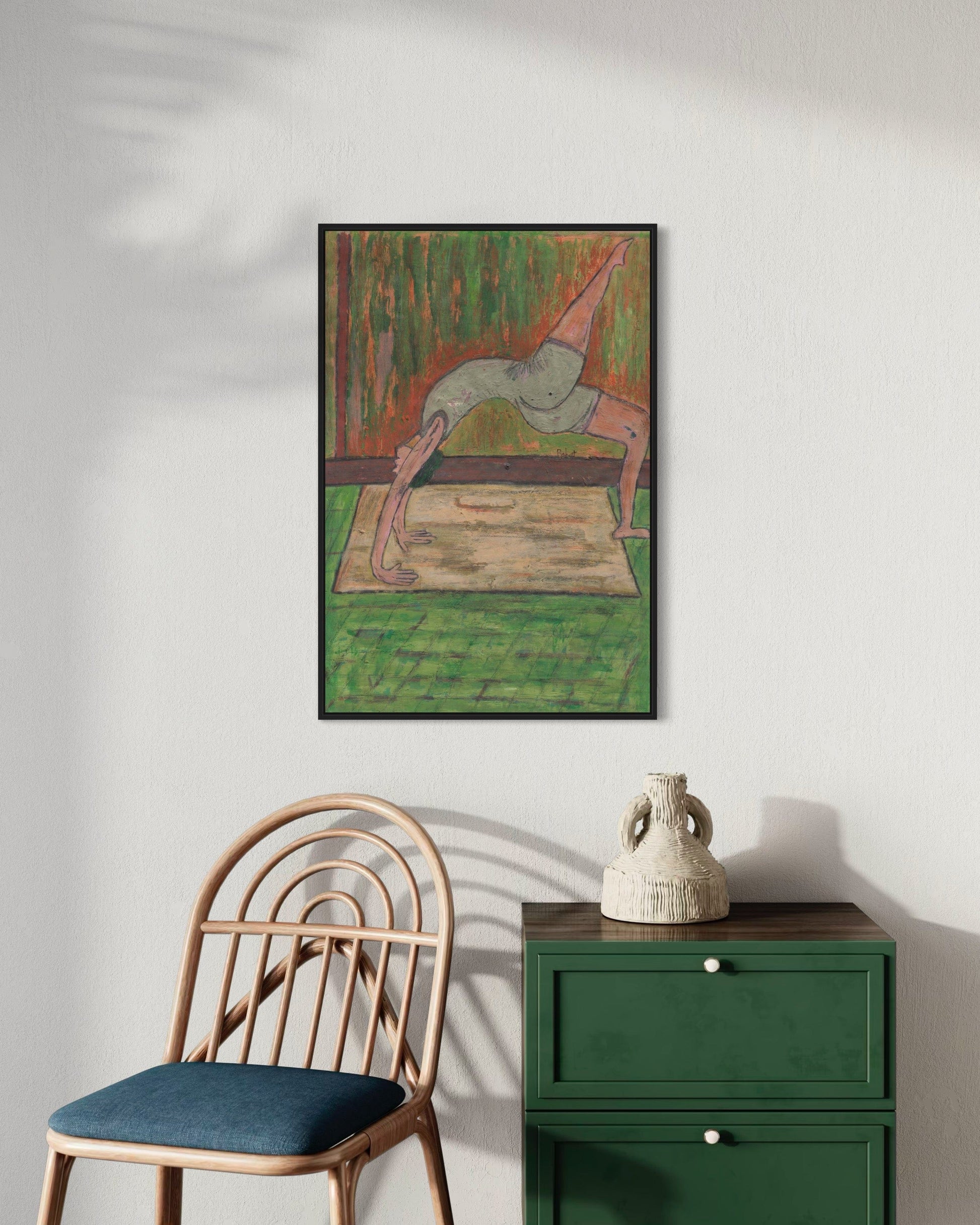 Framed artwork on a wall above a chair and green cabinet