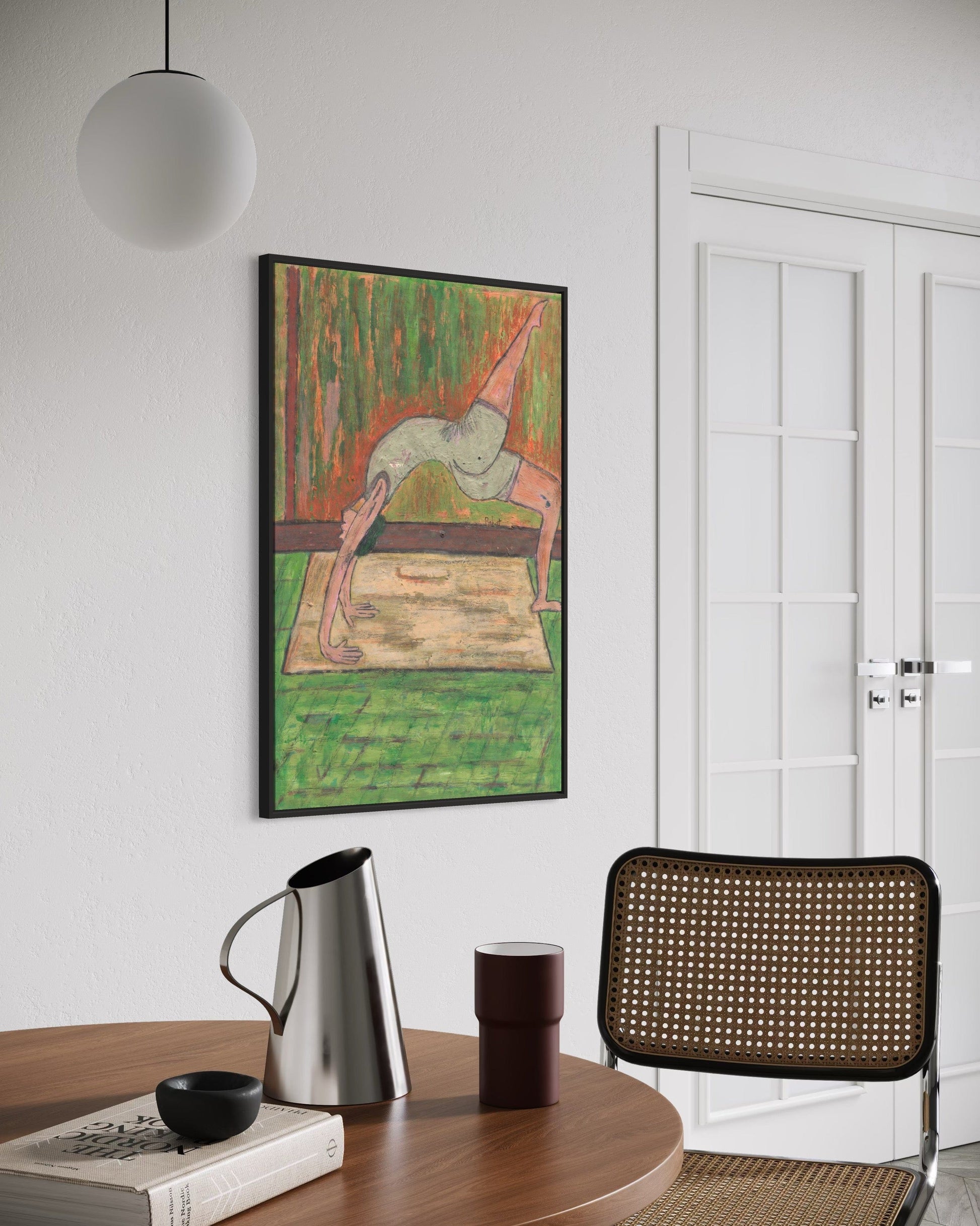 Framed artwork on a wall above a table with a pitcher and glass, next to a chair.