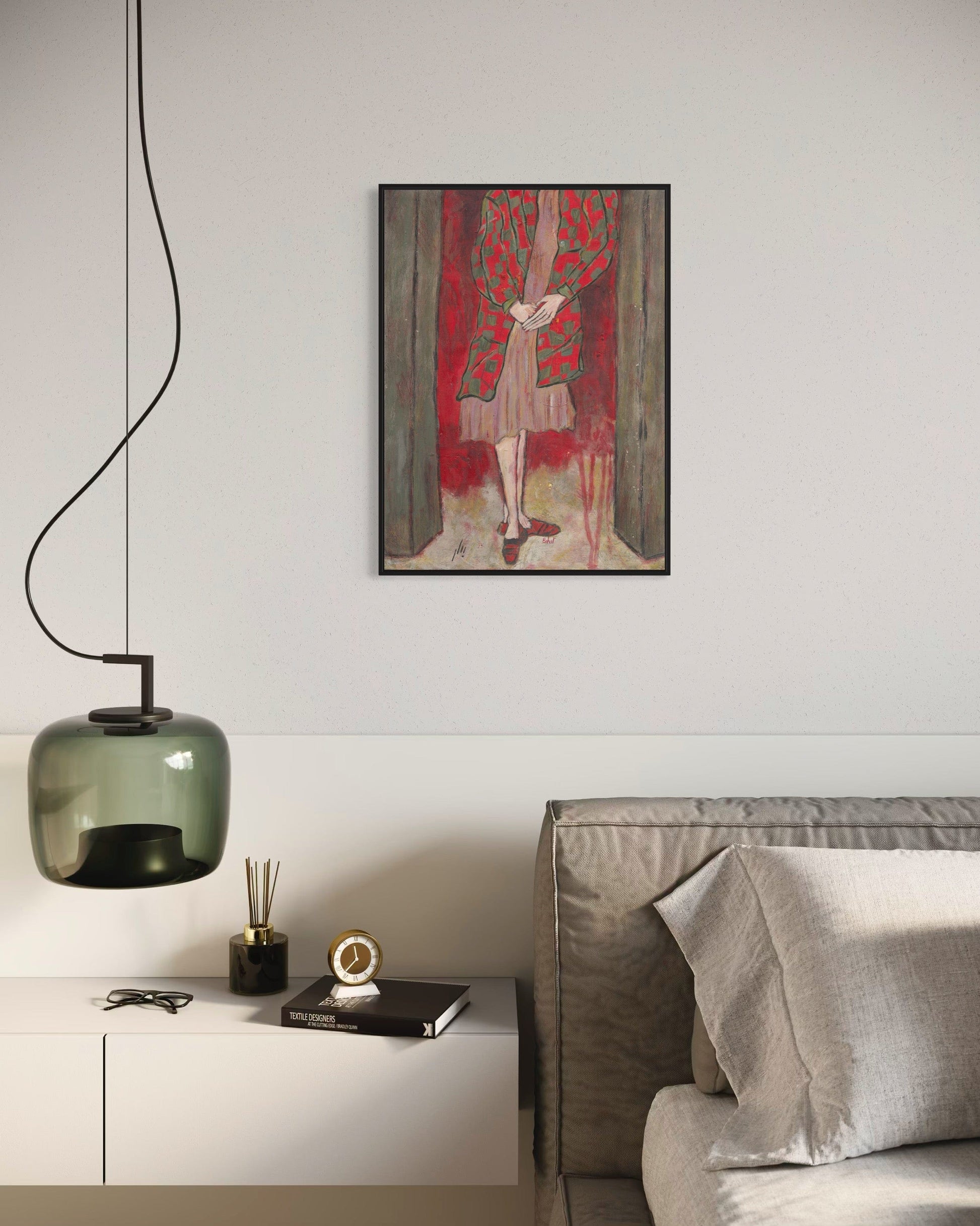 Modern living room with a gray sofa, decorative lamp, and framed artwork on the wall.