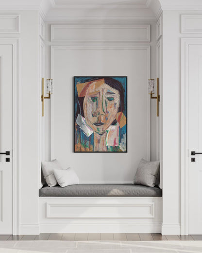 Artistic portrait on a wall above a cushioned bench in a stylish interior.