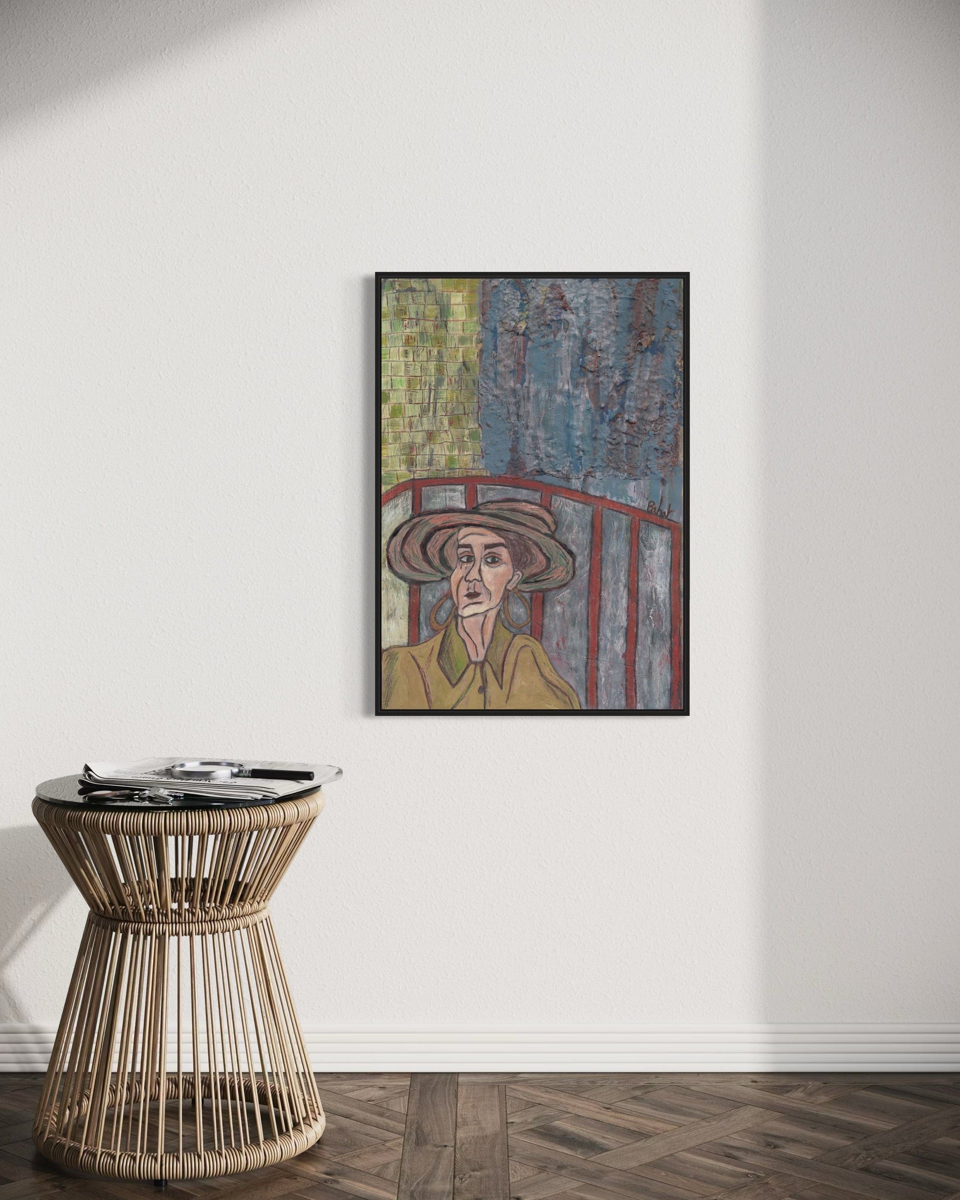 Framed artwork on a wall above a wicker side table.