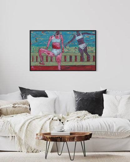 Framed artwork of two figures on a white wall above a white sofa with decorative pillows.