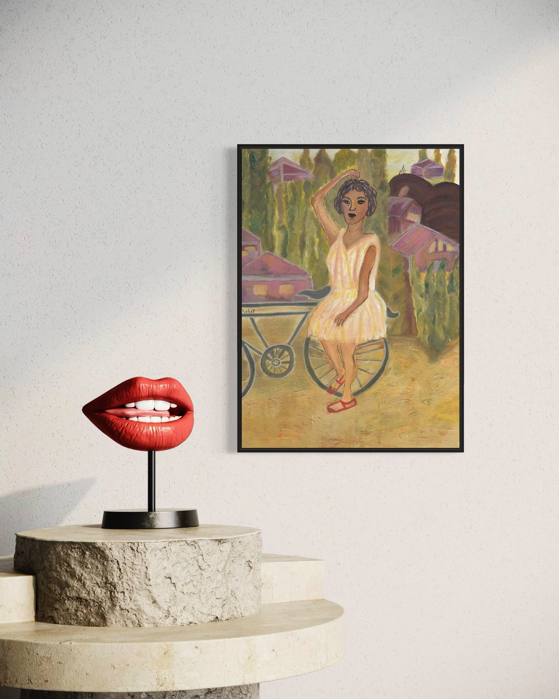 Framed artwork of a woman in a dress next to a red lip-shaped object on a white surface.