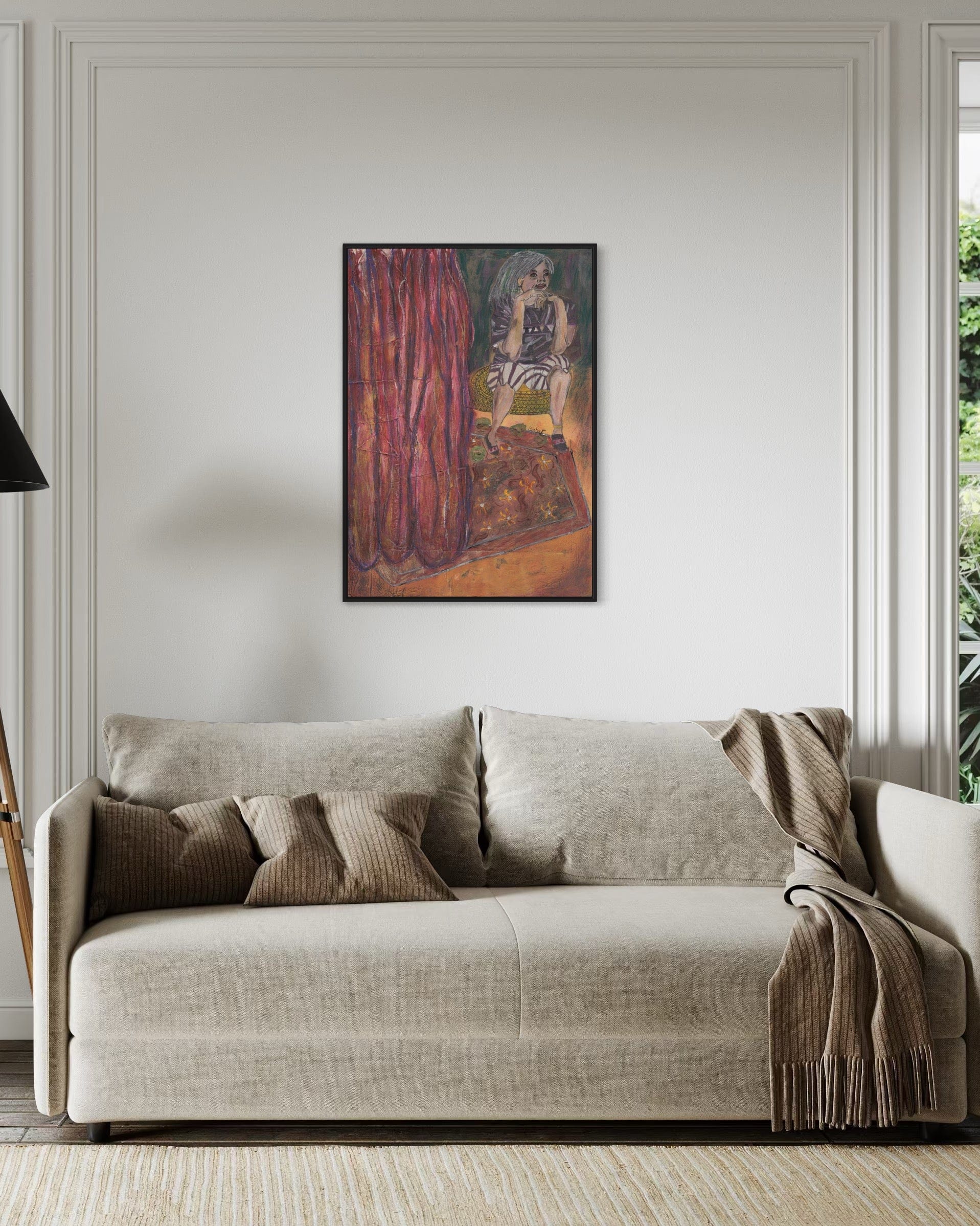Beige sofa with decorative pillows and a blanket in a room with a framed painting on the wall.