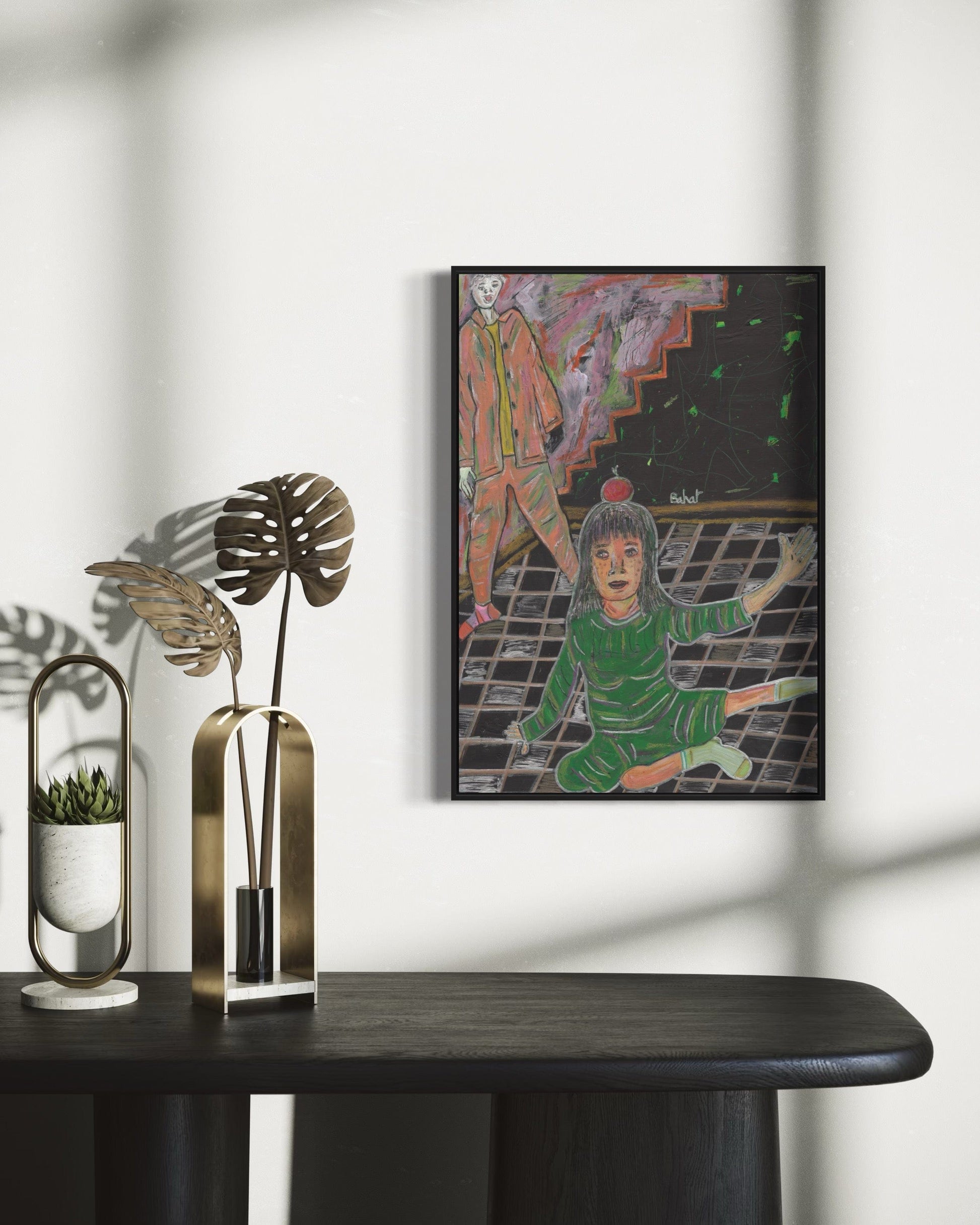 Framed artwork on a wall with decorative items on a table below.