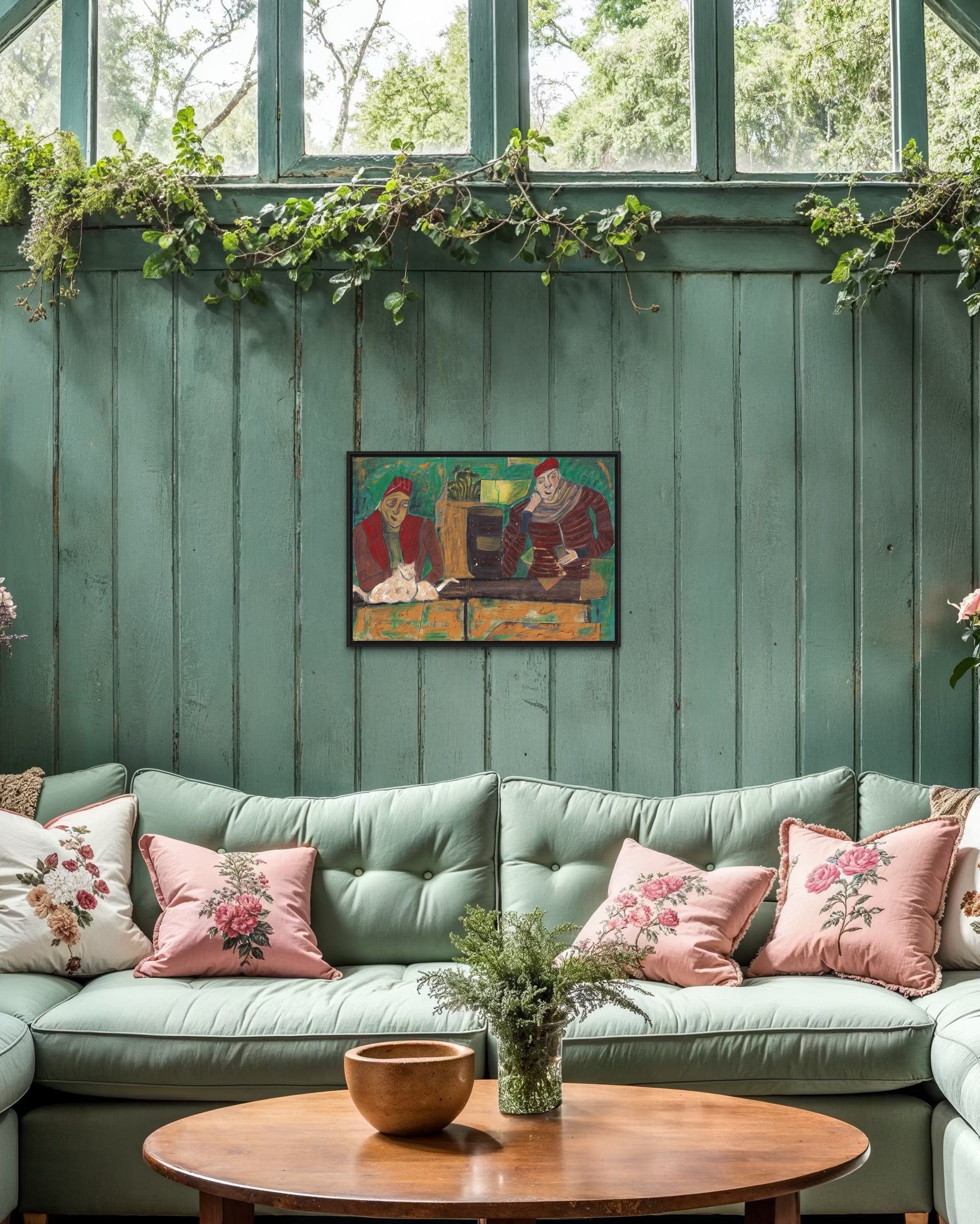 Green sofa with floral cushions in a room with wooden walls and a painting.