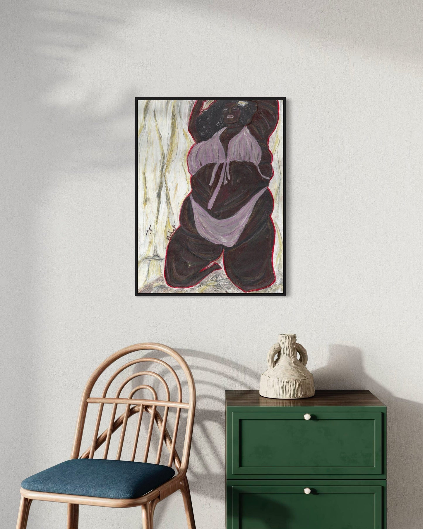 Framed abstract art piece on a wall above a green cabinet and chair.