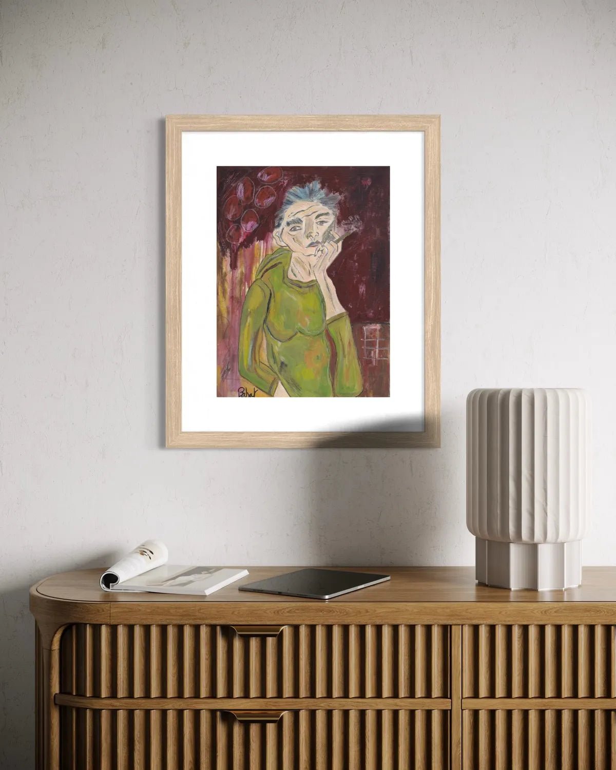 Framed artwork of a person with grey hair on a wall above a wooden console table.