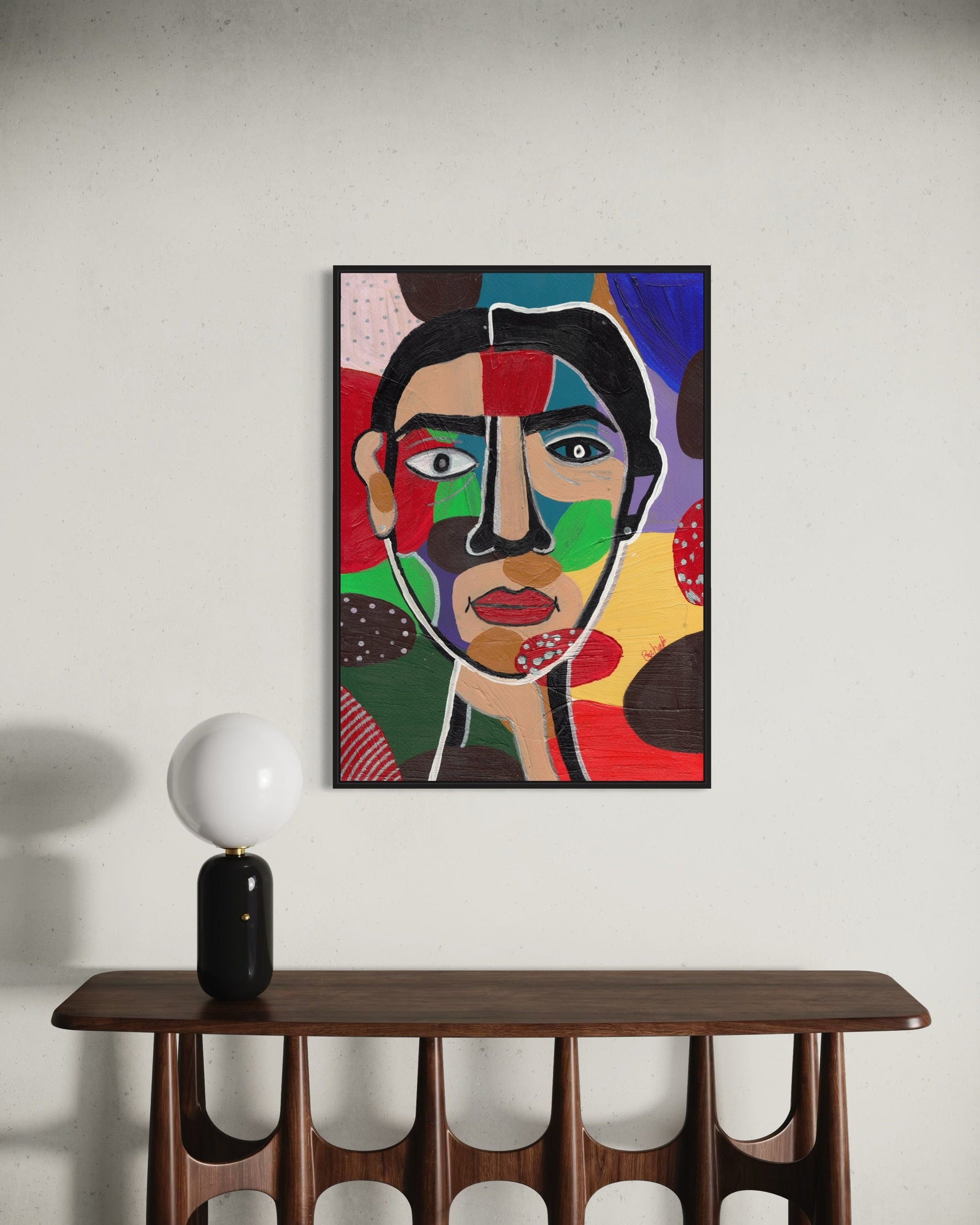 Colorful abstract painting of a face on a wall above a wooden console table.