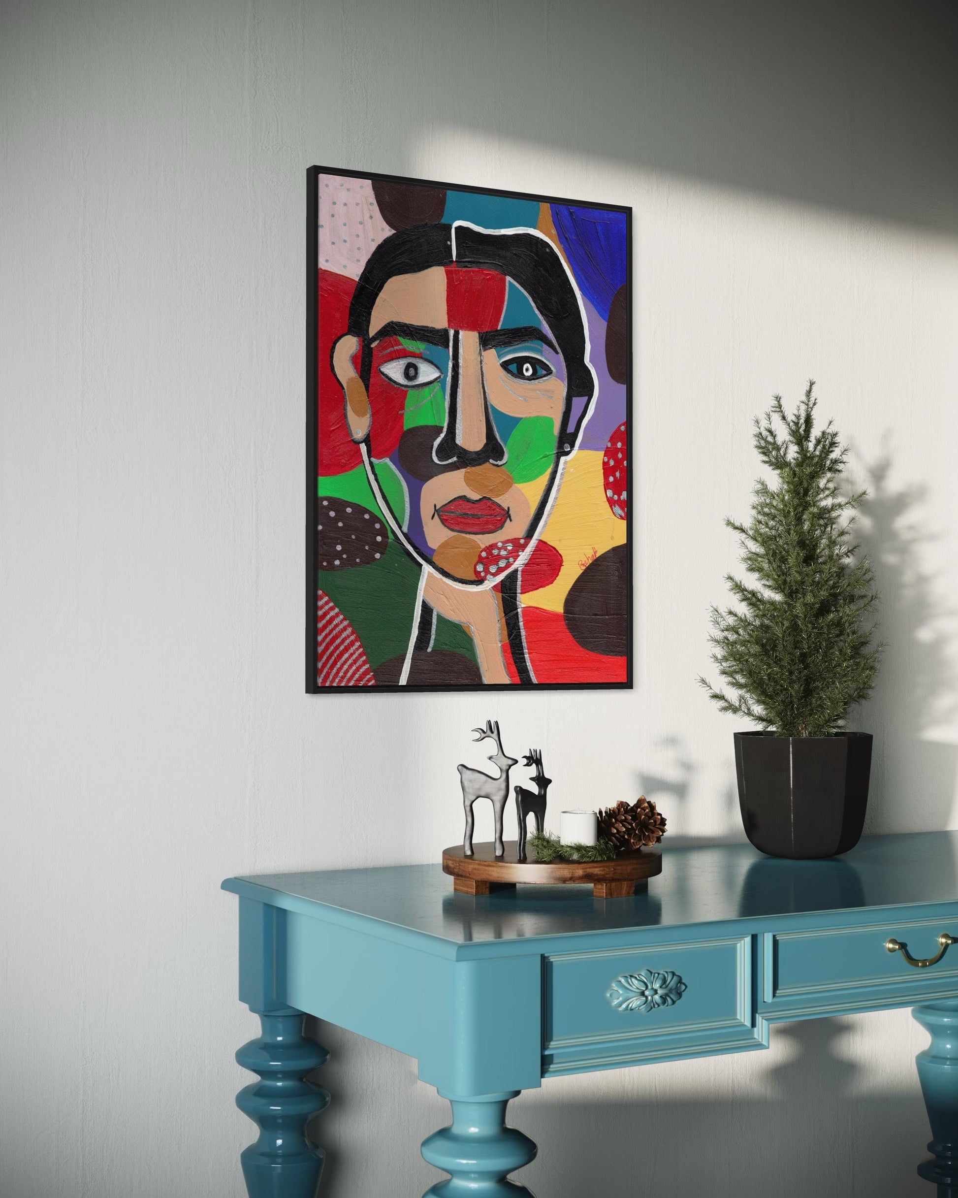Colorful abstract painting on a wall above a blue table with decorative items.
