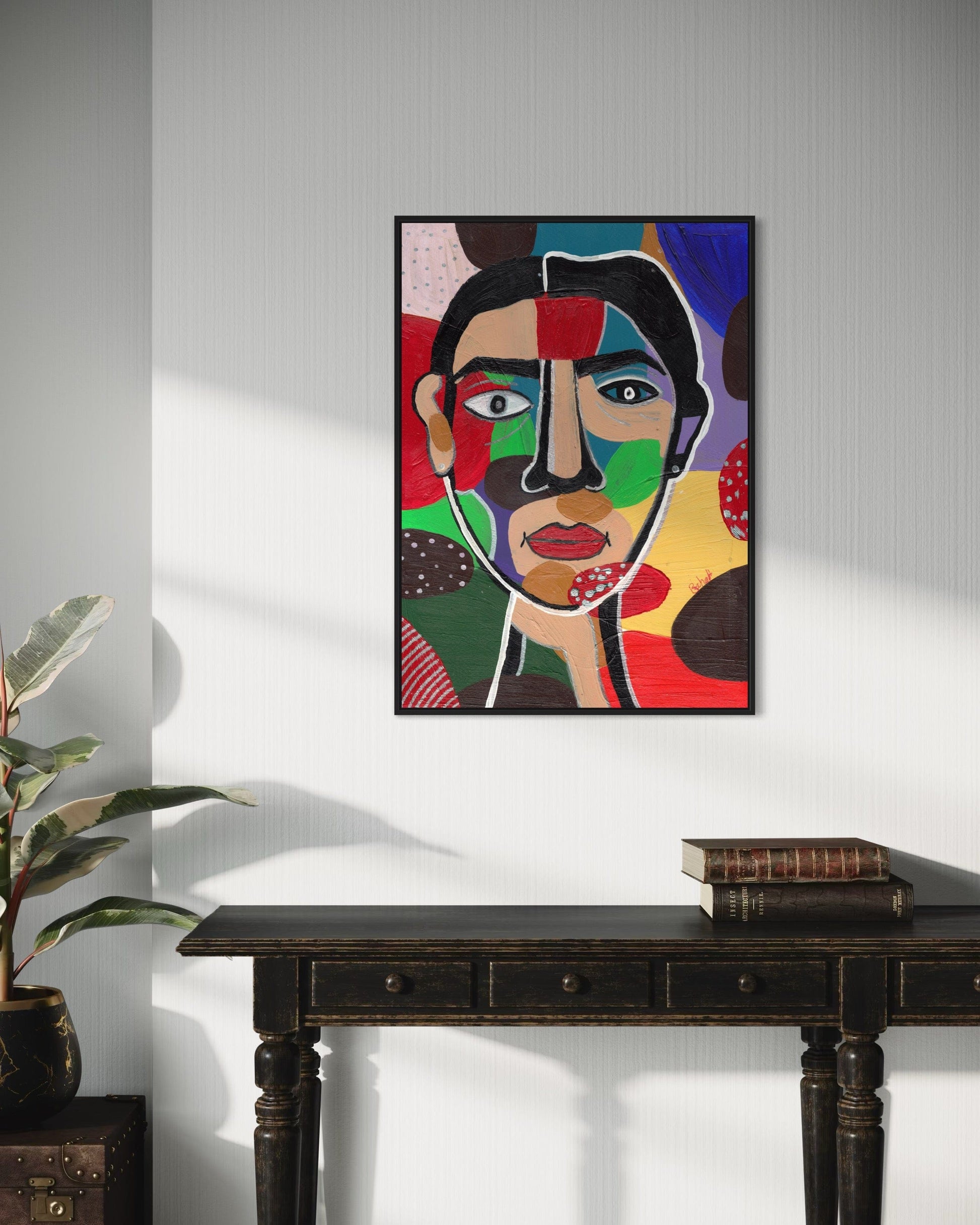 Colorful abstract portrait painting on a wall above a dark wooden table.
