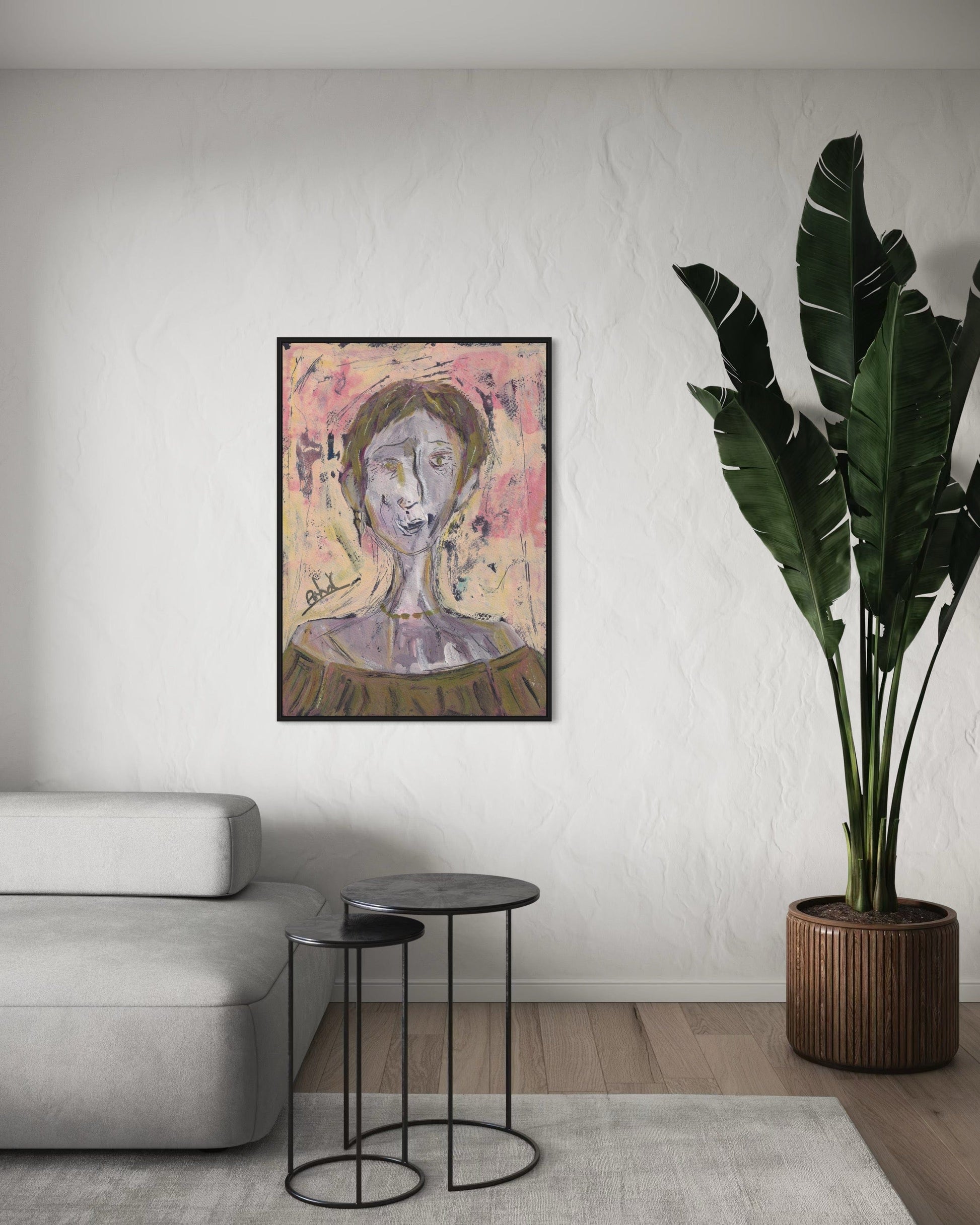 Framed artwork on a wall in a living room with a sofa and plant.