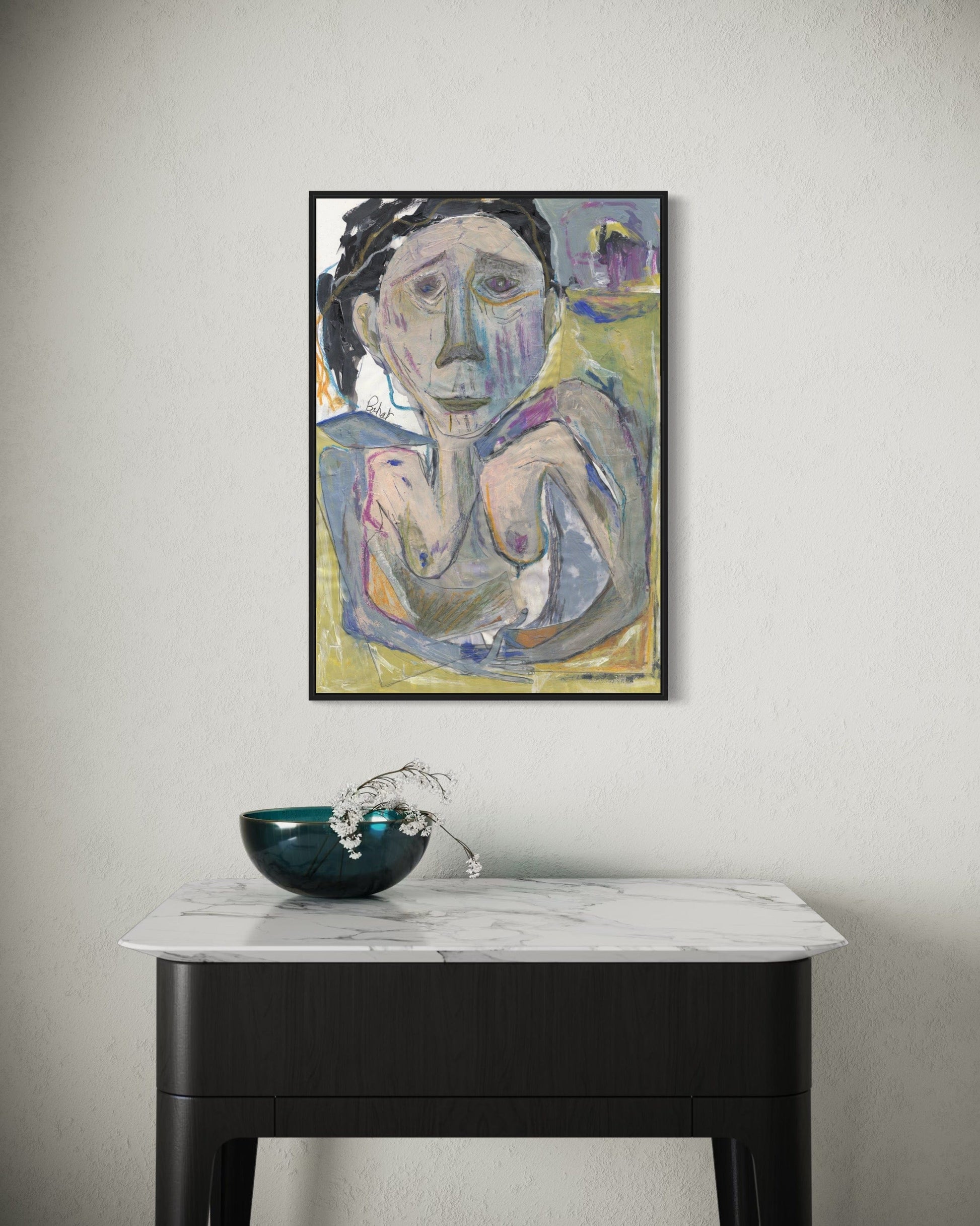 Framed abstract painting on a wall above a marble table with a decorative bowl.