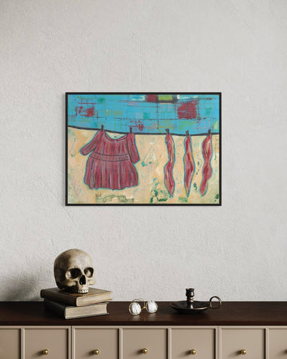 Framed abstract painting of clothes on a line above a shelf with decorative items.
