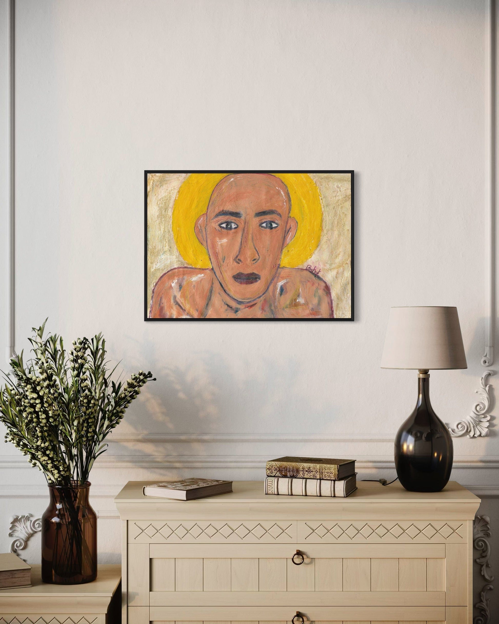 Framed artwork of a stylized face on a wall above a cabinet with decorative items.