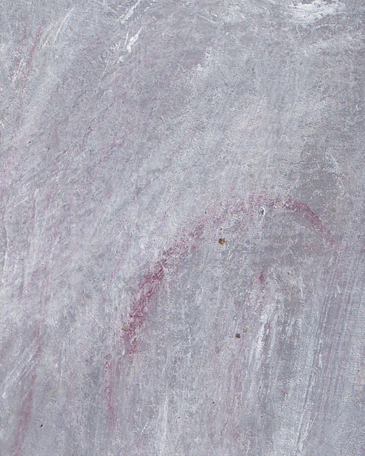 Close-up of a textured gray surface with a red stain.