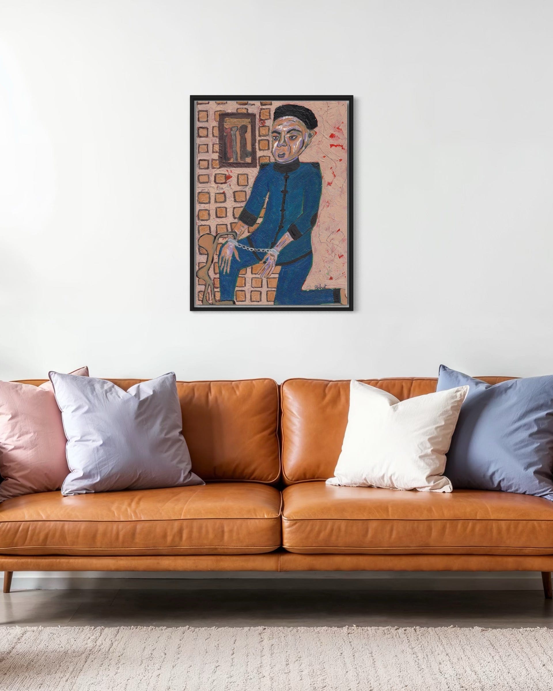 Framed artwork above a brown leather sofa with colorful cushions.