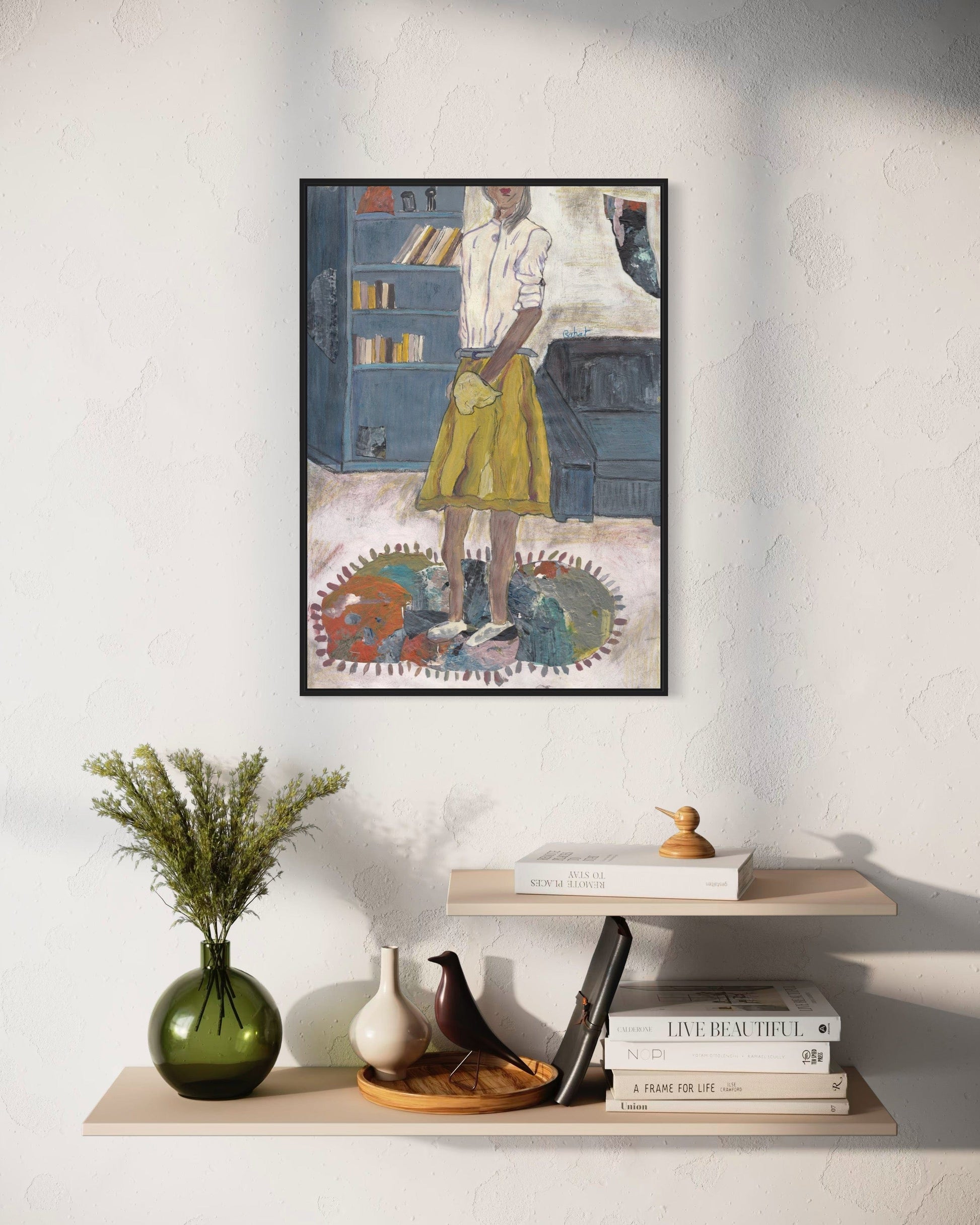 Framed artwork on a wall above a shelf with decorative items