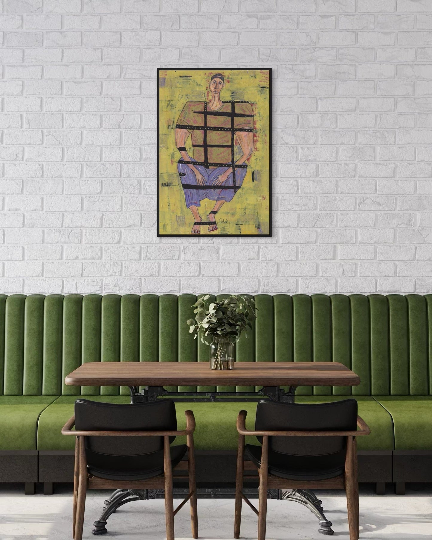 Green booth with wooden table and chairs against a white brick wall with a colorful abstract painting.