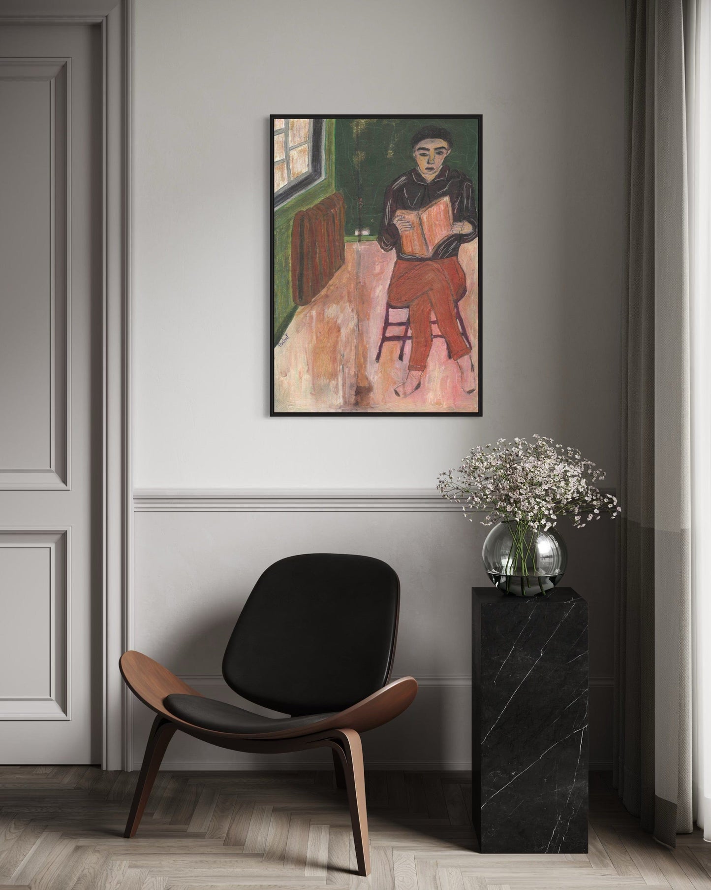 Modern interior with a black chair, side table, and framed artwork on a gray wall.