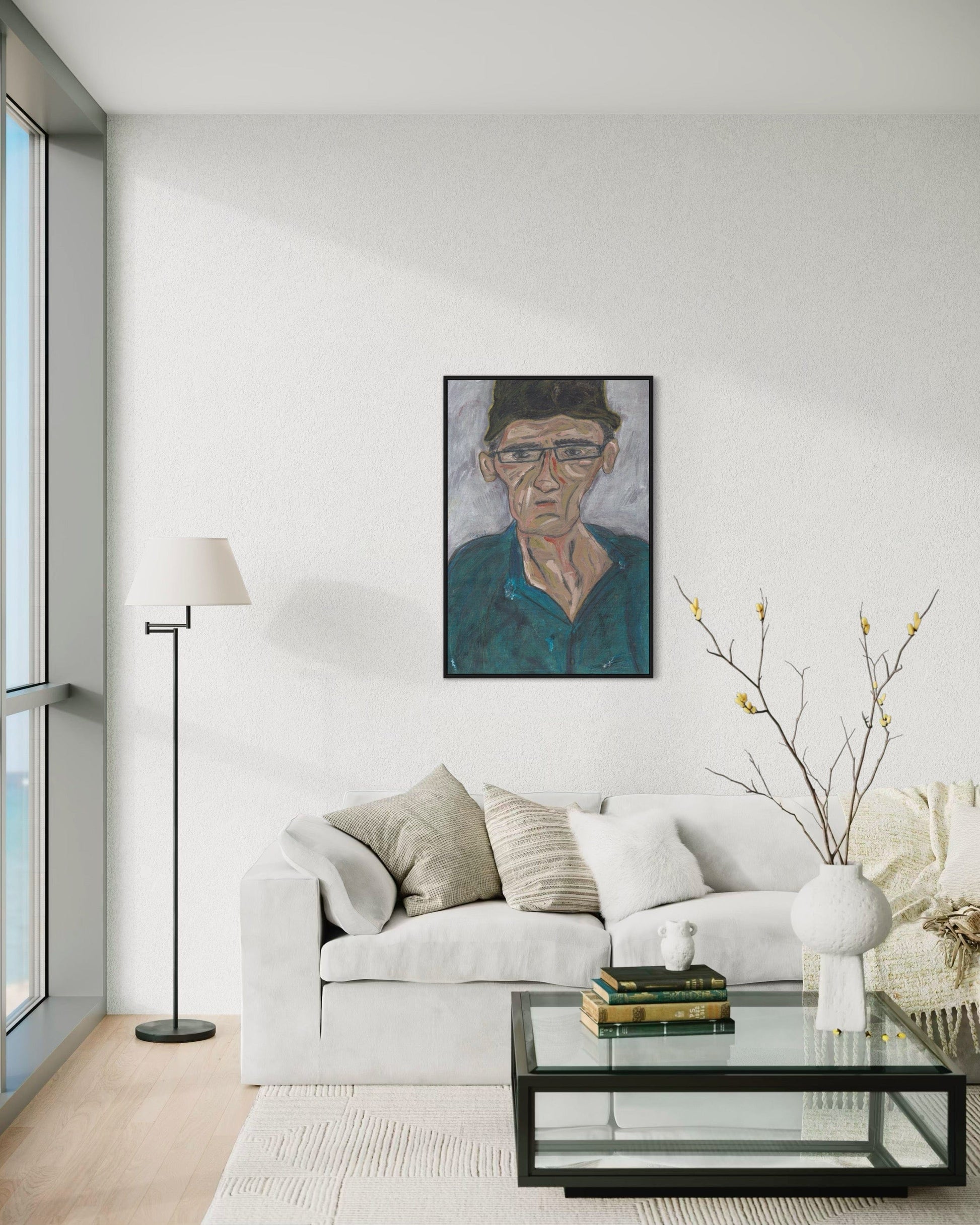 Modern living room with a white sofa, glass coffee table, and framed portrait on the wall.