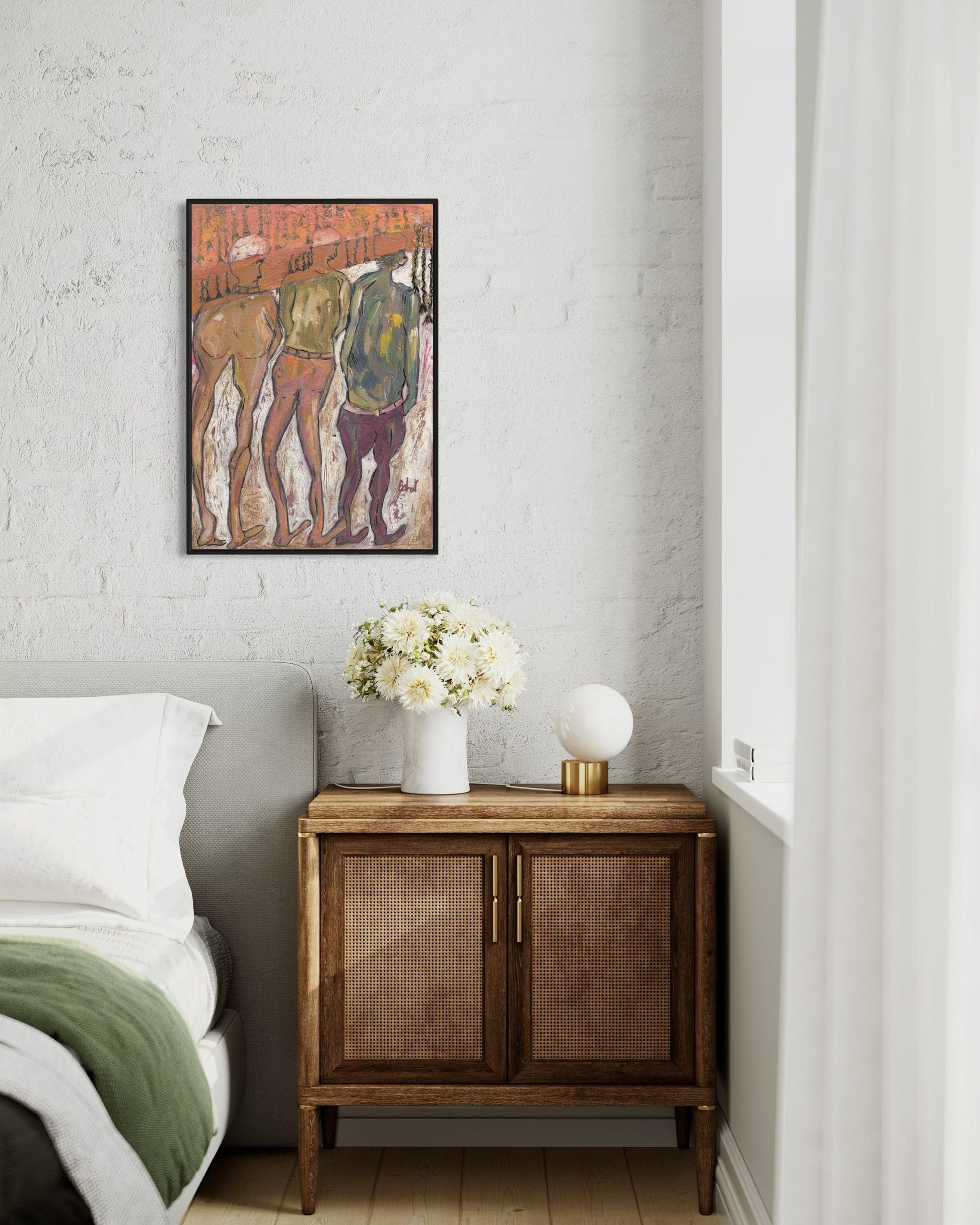 Wooden side table with a vase of flowers next to a bed, with a framed artwork on the wall.