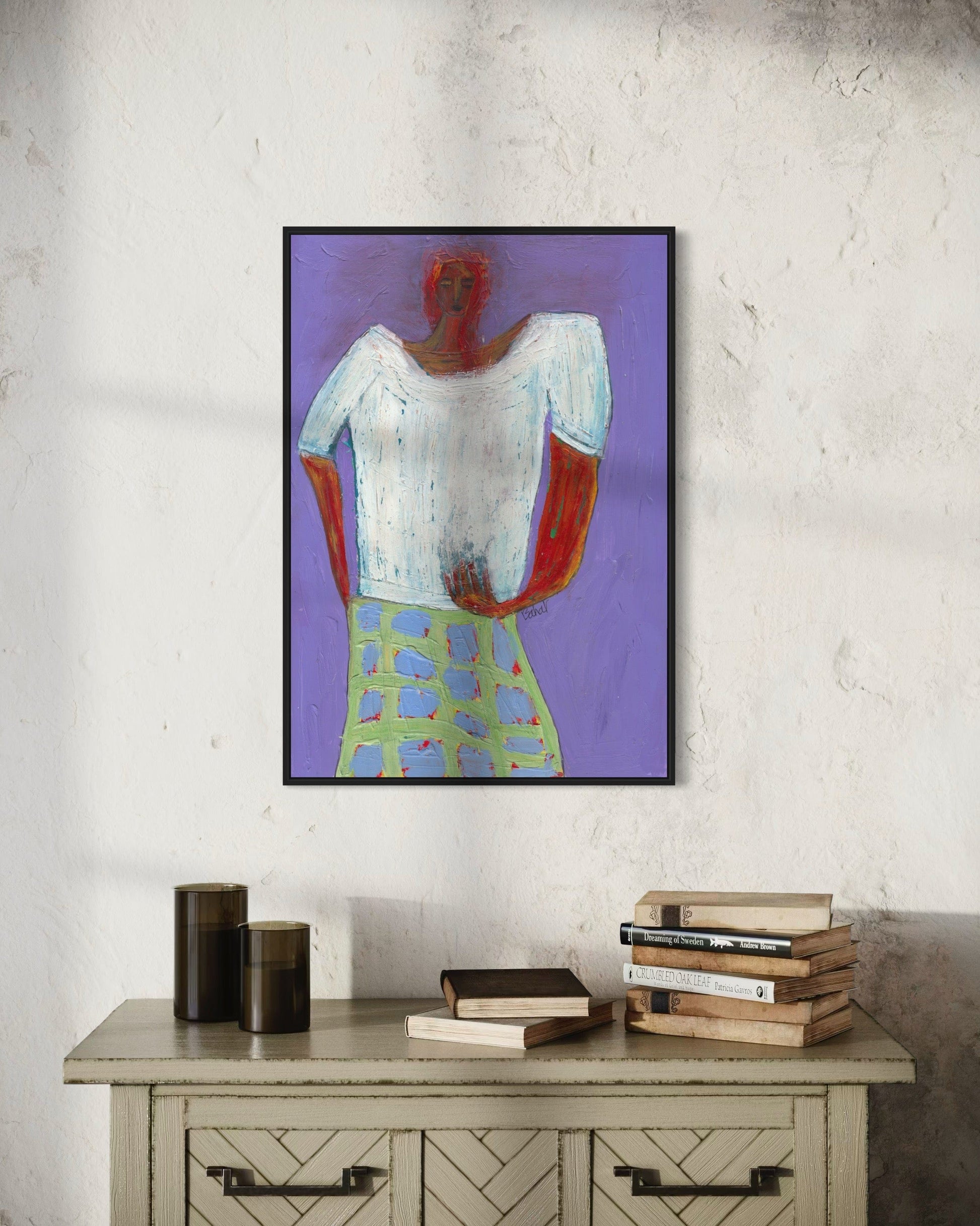Framed abstract art on a wall above a wooden cabinet with books.